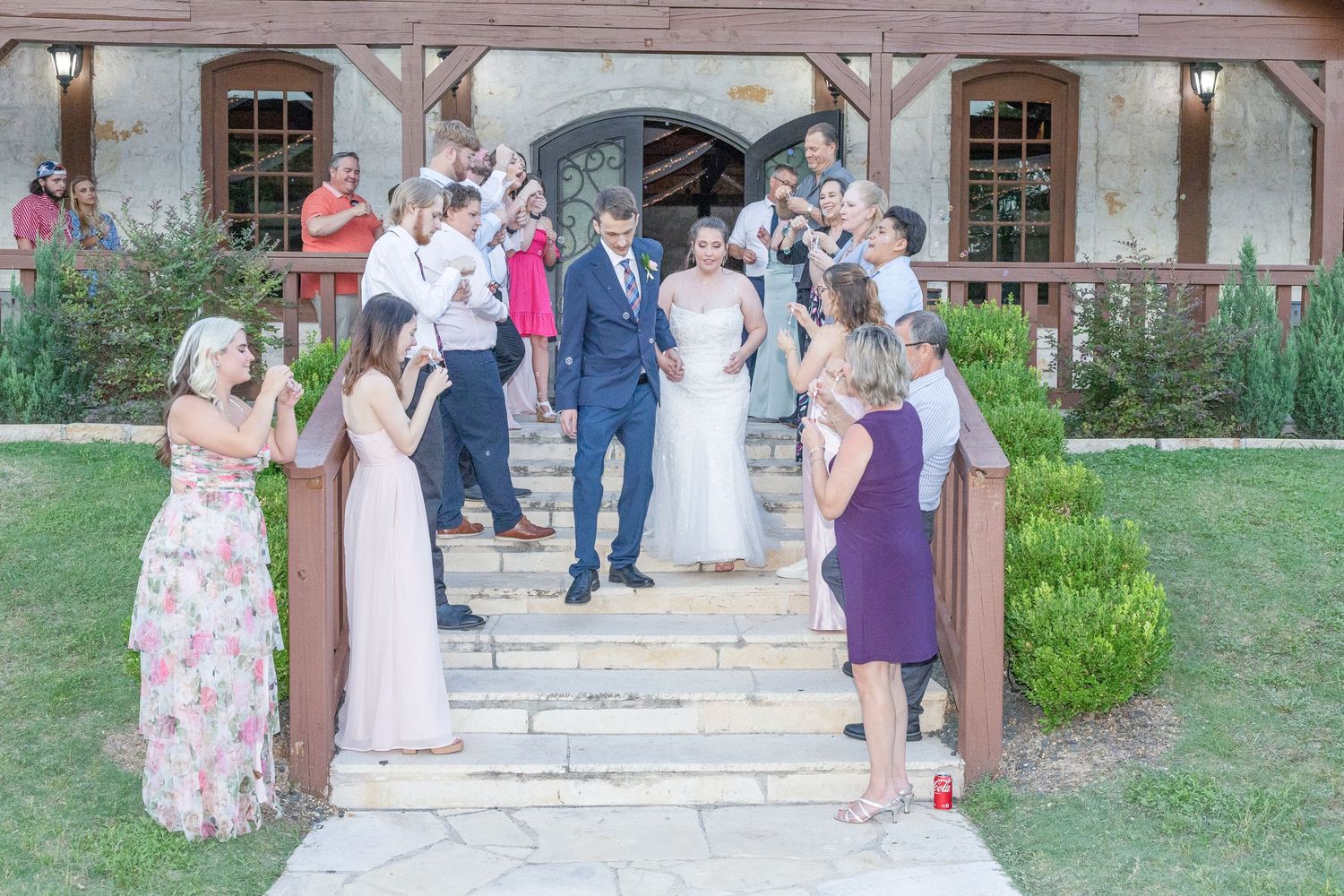 Wedding guests gather under a rustic wooden pavilion during an outdoor summer celebration.