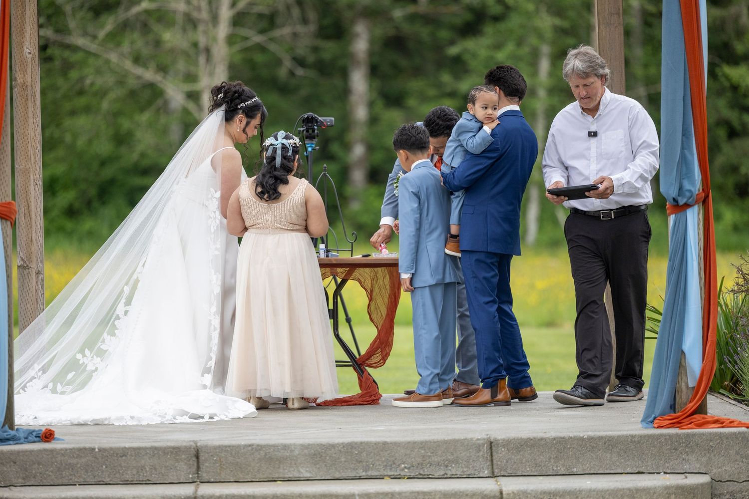 Newlyweds share a tender moment during their outdoor wedding ceremony beneath a rustic wooden arbor.