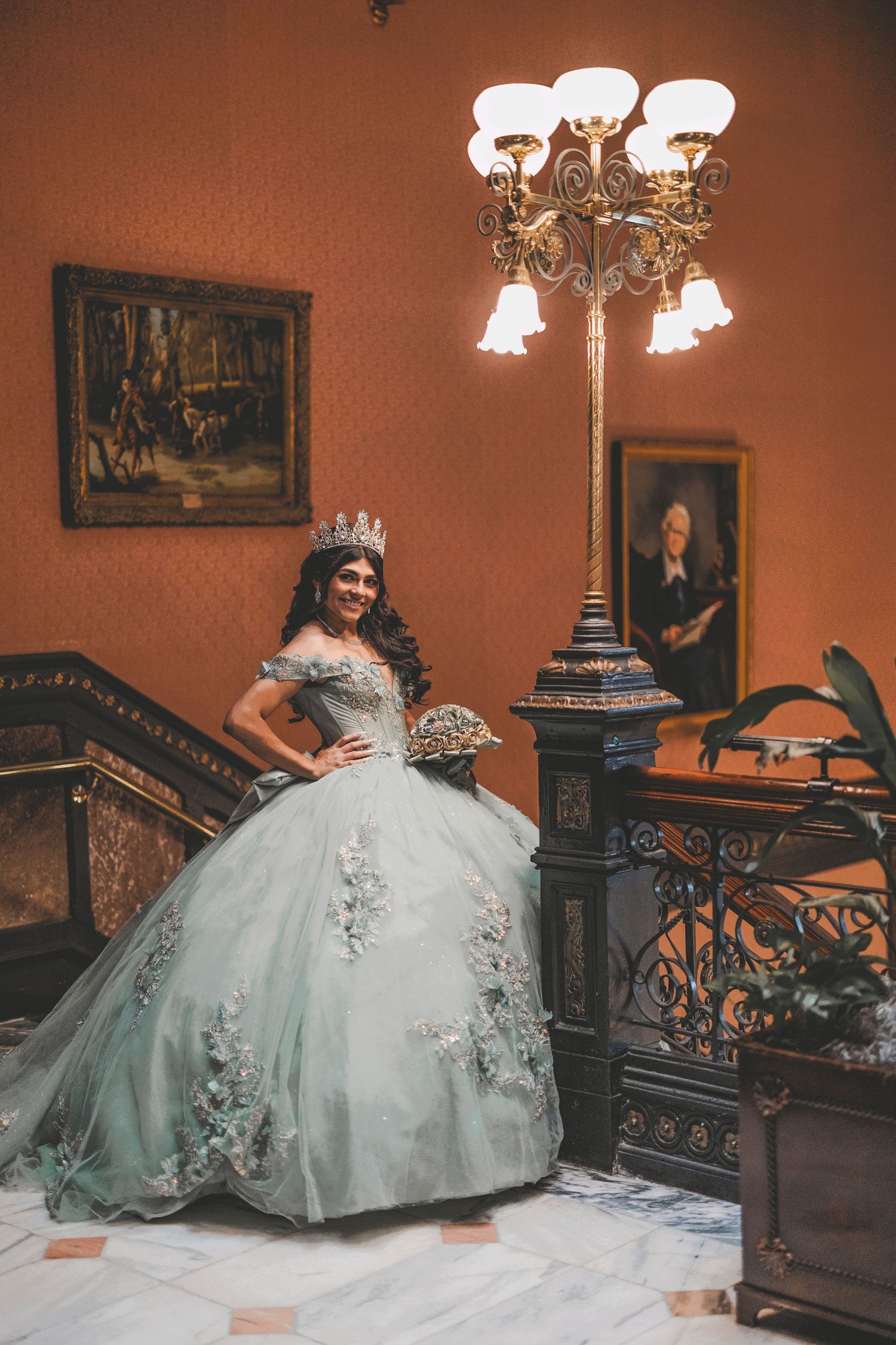 A stunning mint green quinceanera dress displayed in an elegant vintage room with antique furniture and warm lighting.