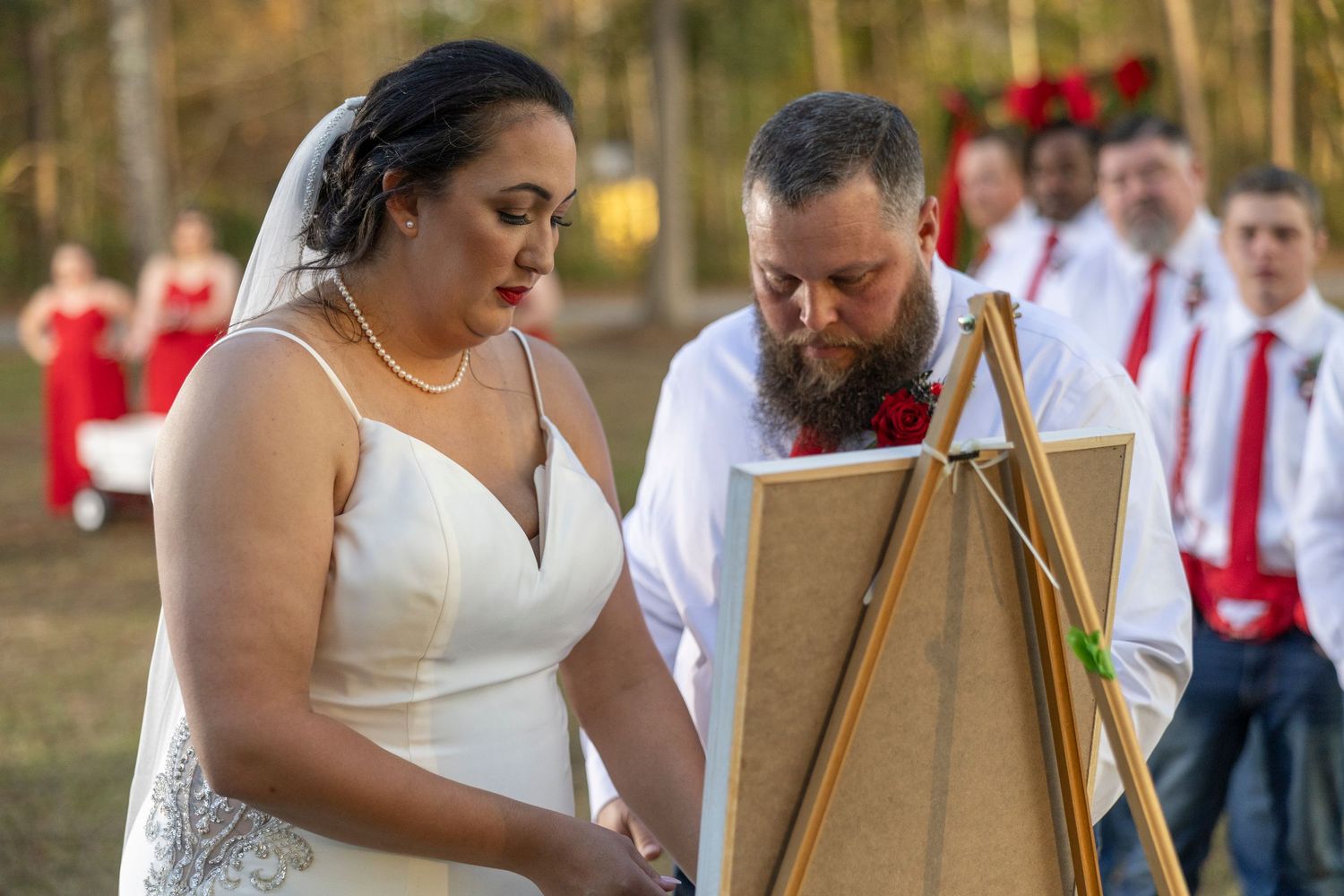 Couple plays wooden limbo game at outdoor wedding reception while guests watch and cheer.