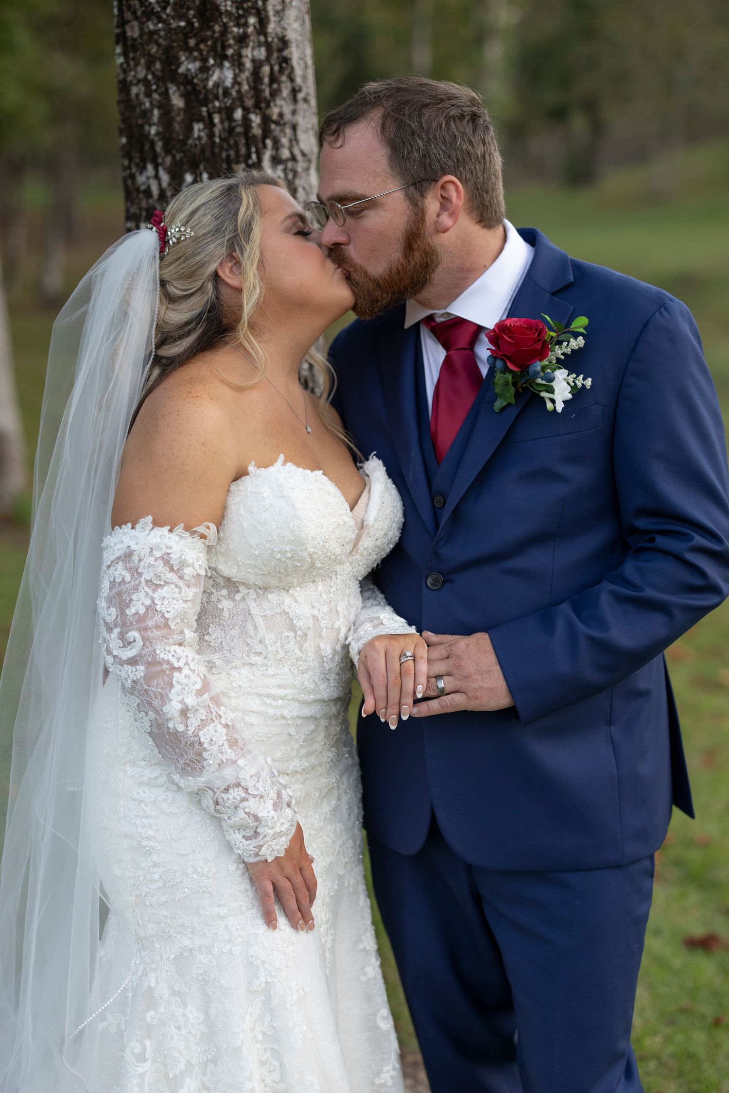 Romantic wedding couple sharing intimate kisses in an outdoor setting with trees in the background.