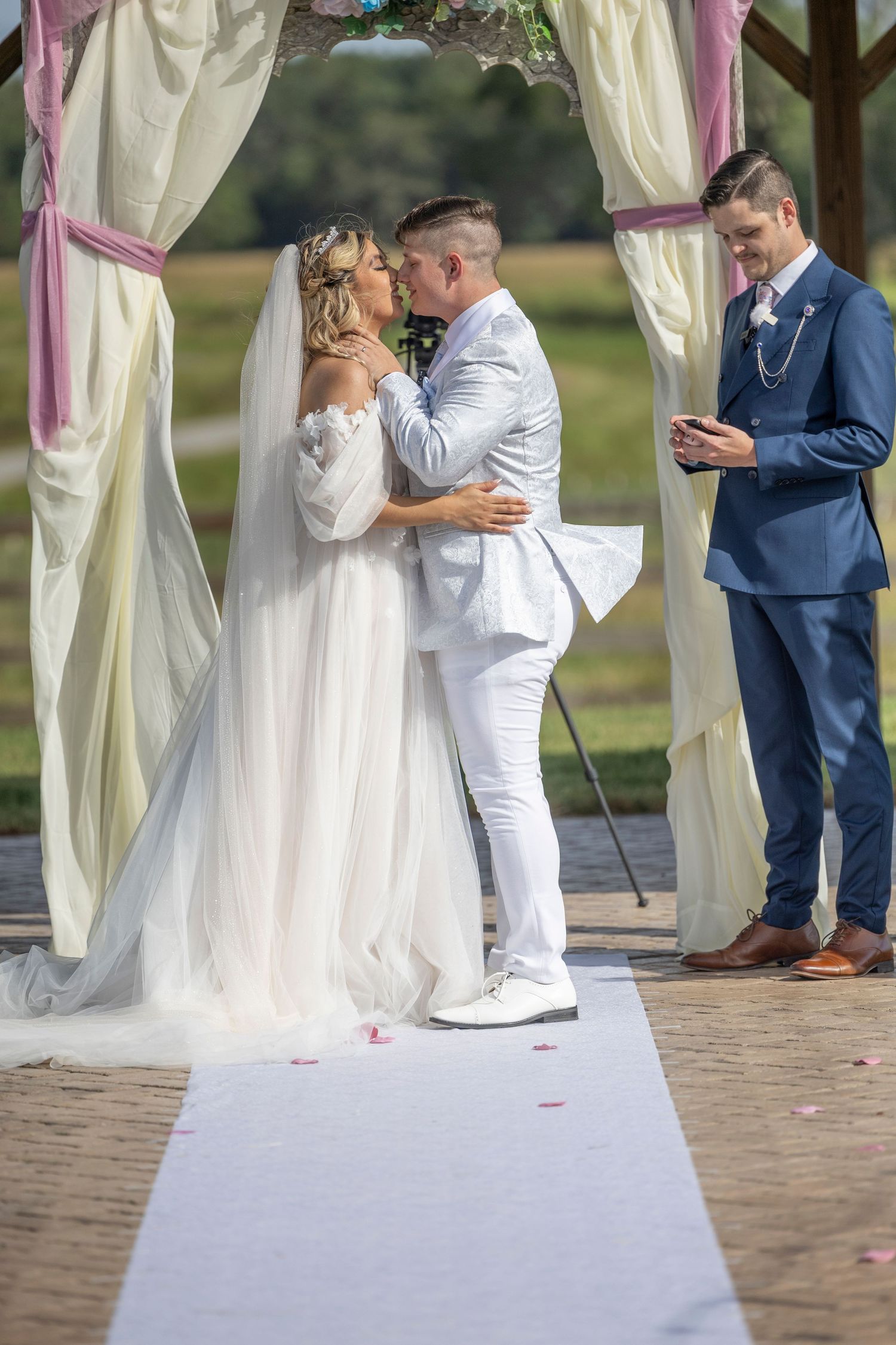 A romantic wedding ceremony sequence showing a couple sharing their first kiss under a draped outdoor pavilion.