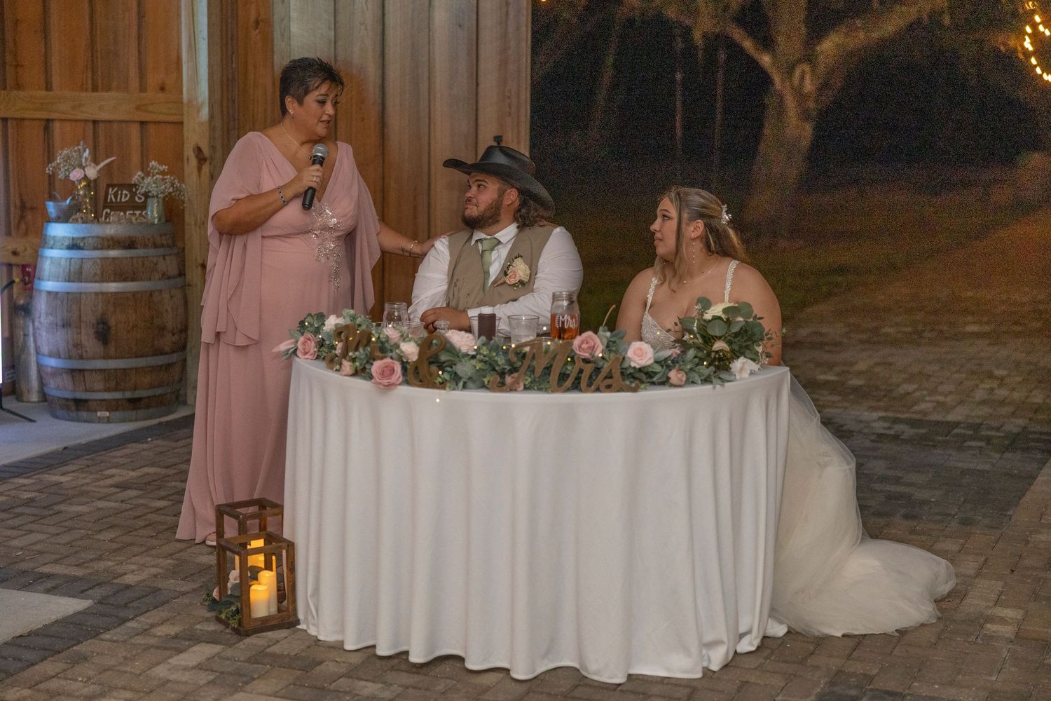 A romantic wedding reception at night with soft lighting, floral centerpieces, and elegant table settings.