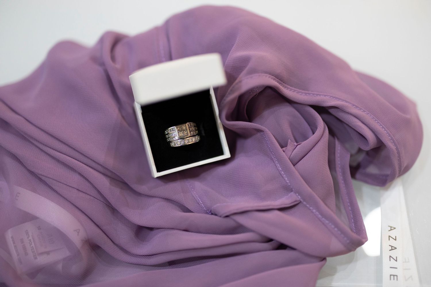 A soft purple scarf is elegantly draped and folded against a white background.