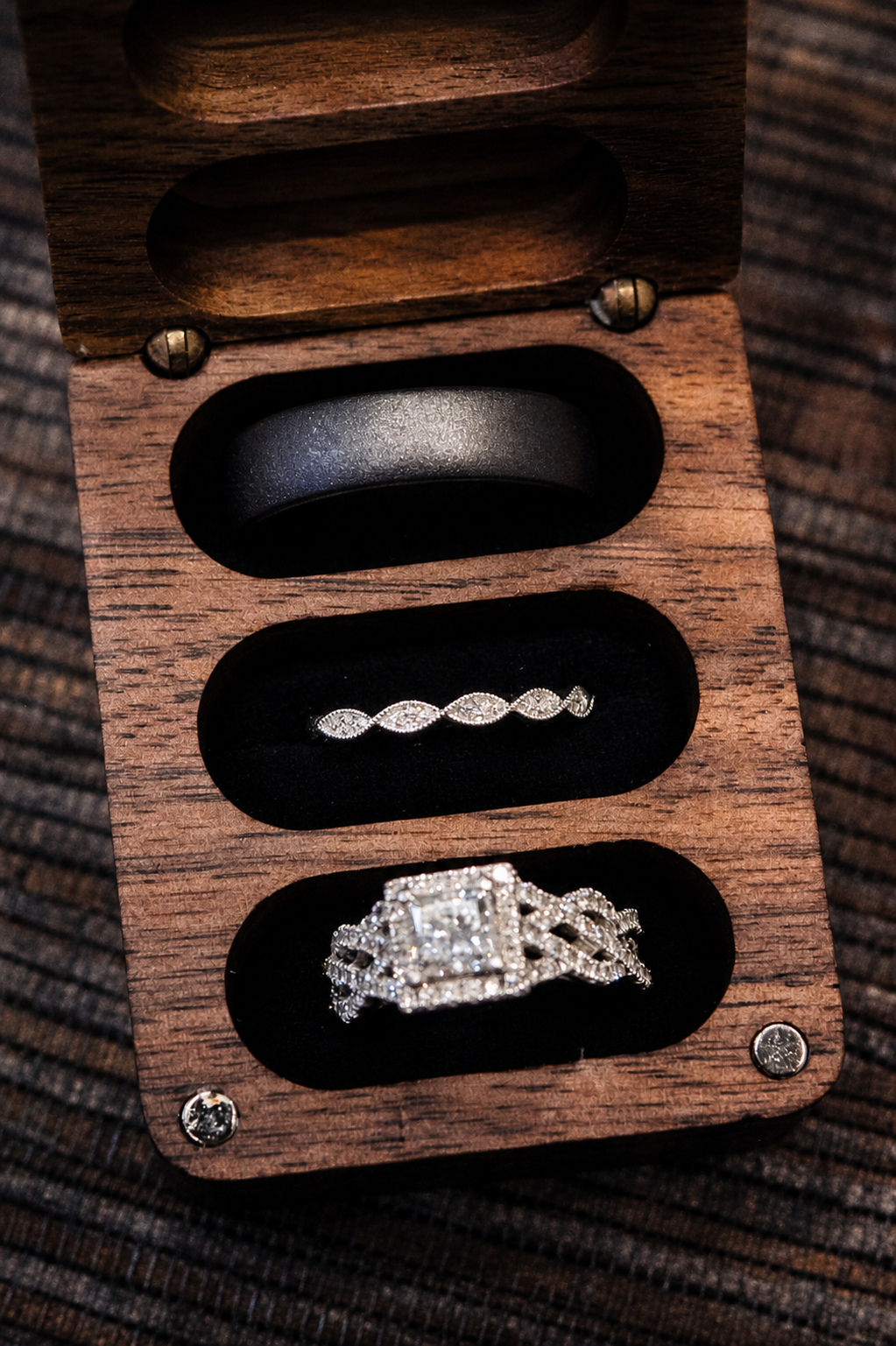 Elegant wedding ring set displayed in a wooden ring box with black velvet slots.