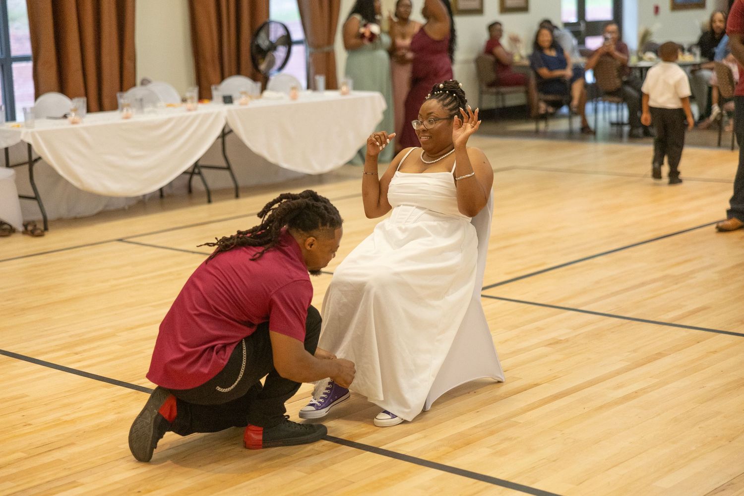 Students crawl on a gymnasium floor during a fun team-building exercise with white sheets and fabric.