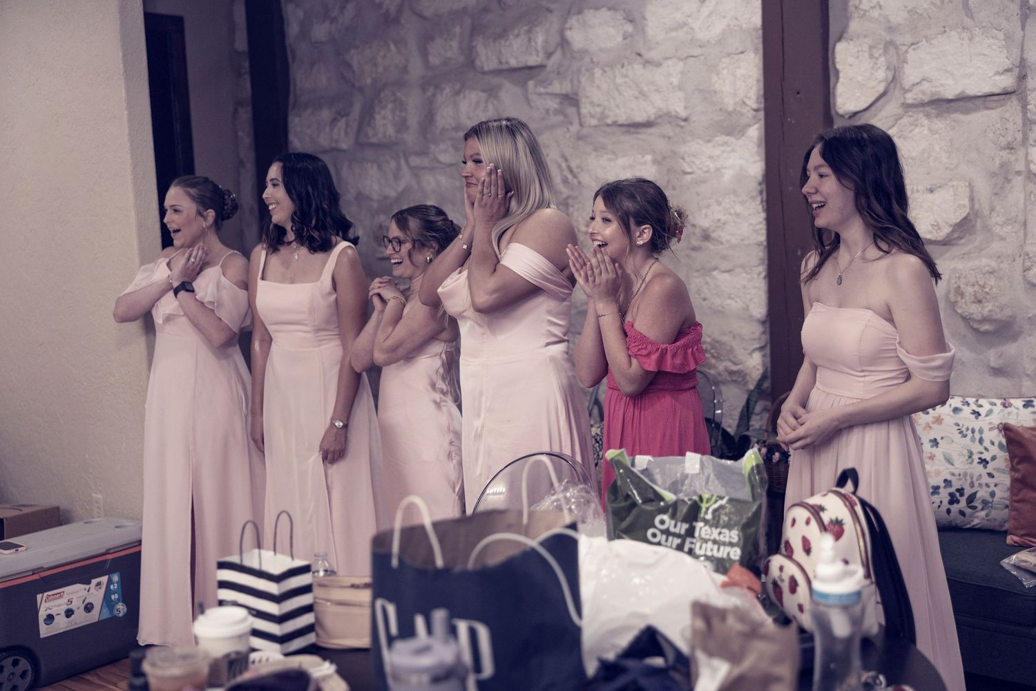 A group of people dancing and celebrating at a party in a room with stone walls.