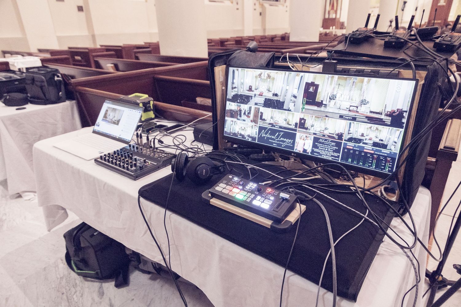 Professional video production setup with multiple monitors and control panels on tables covered in white tablecloths.