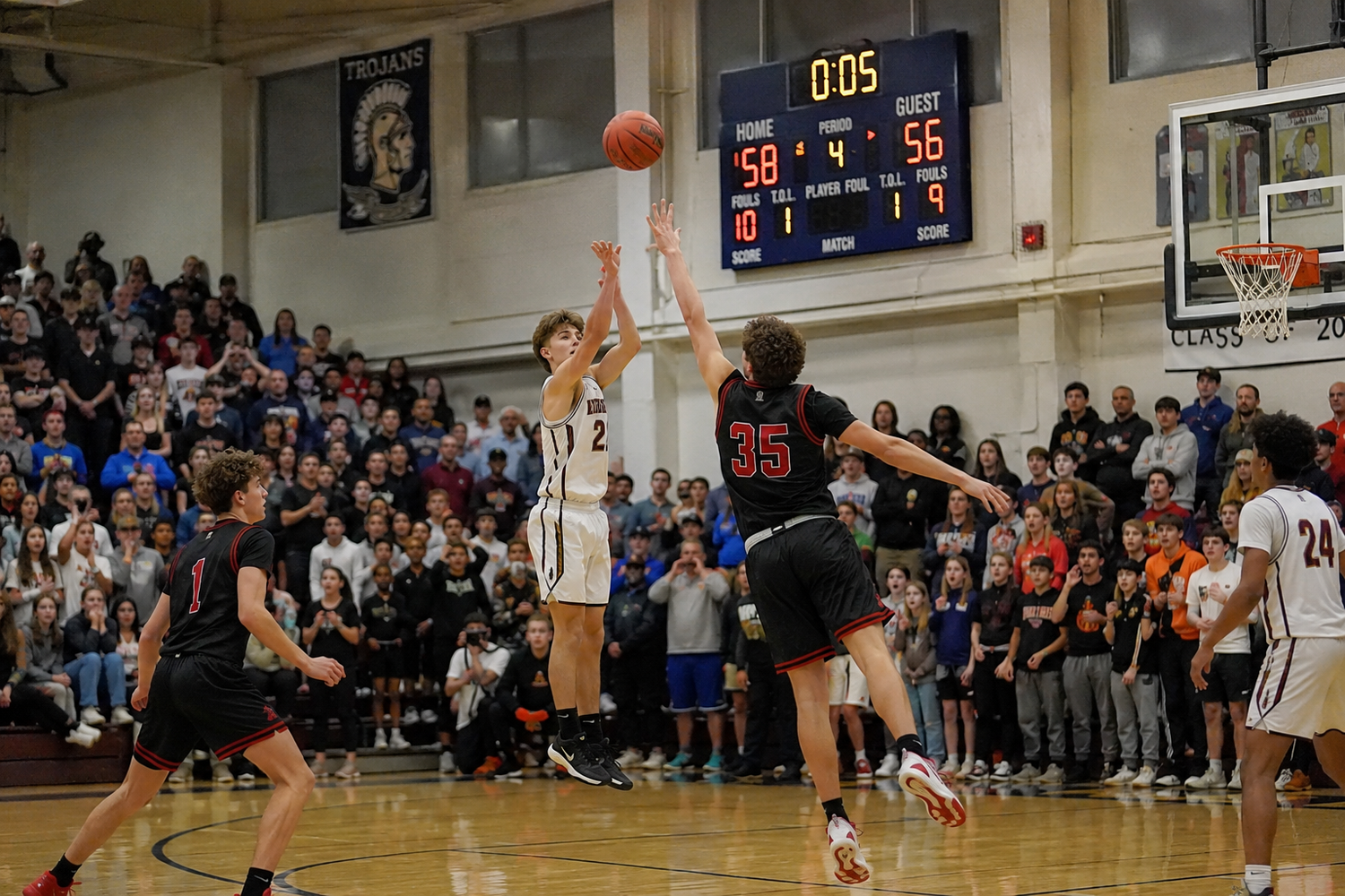Player shoots a last-second buzzer-beater as scoreboard shows 58-56 in a packed high school gym.