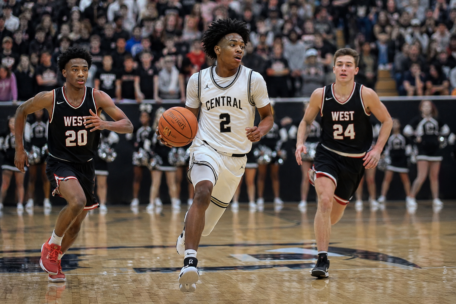 Central player #2 drives to the basket past two West defenders during a high school basketball game.