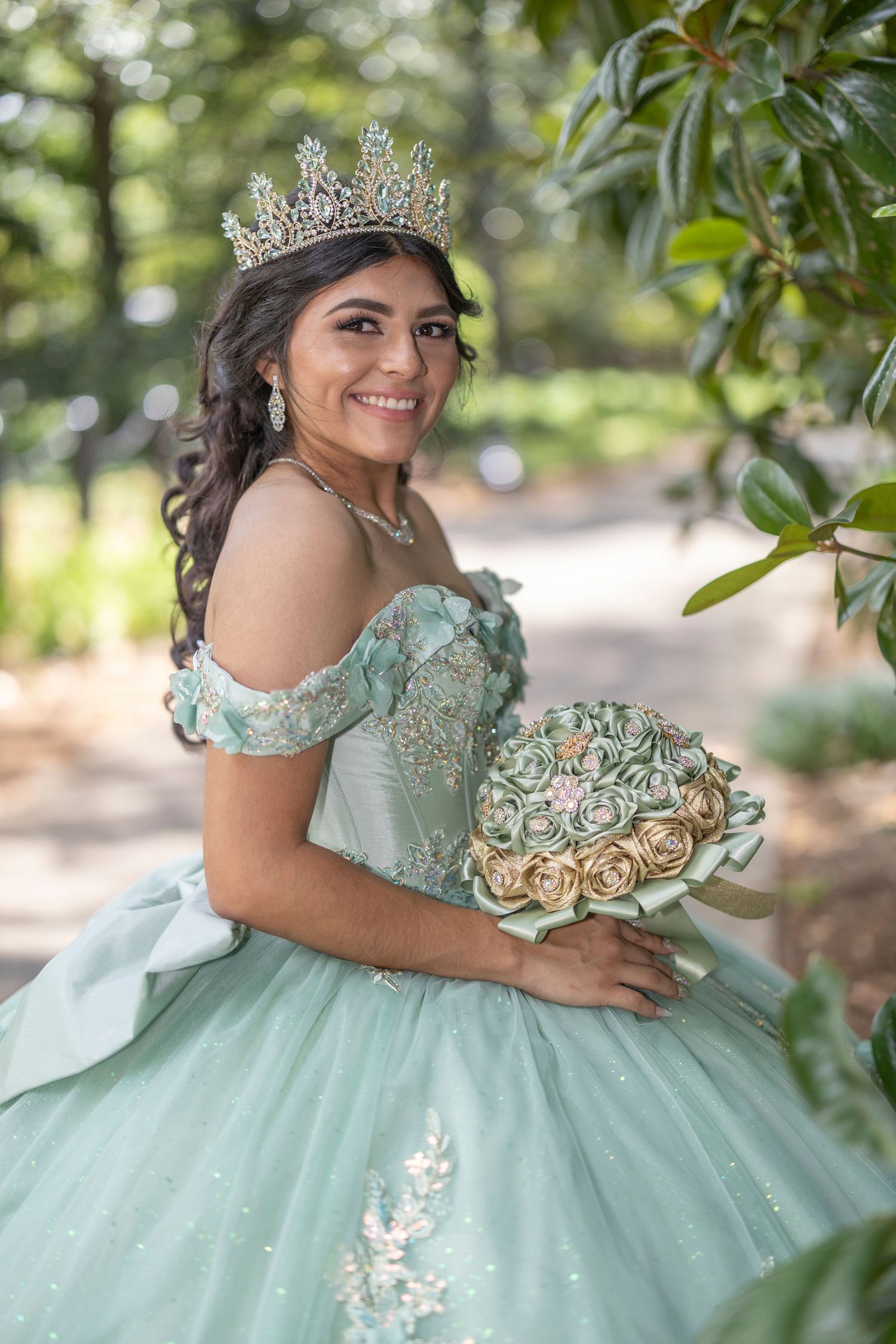 A quinceañera celebration features a mint green ball gown with delicate embellishments in an outdoor garden setting.