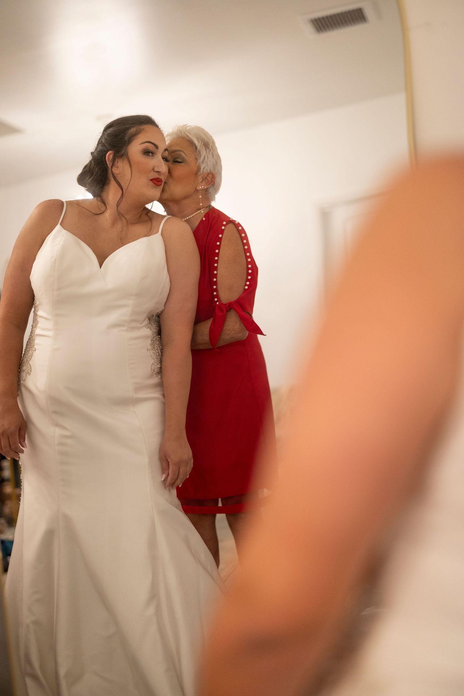 A couple embraces during a special moment, one wearing a white gown and the other in a red dress.