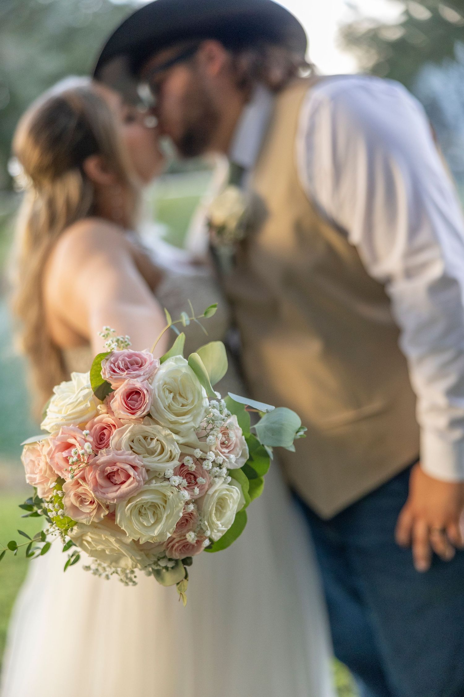 A romantic wedding moment with a beautiful bouquet of pink and white roses in the foreground.