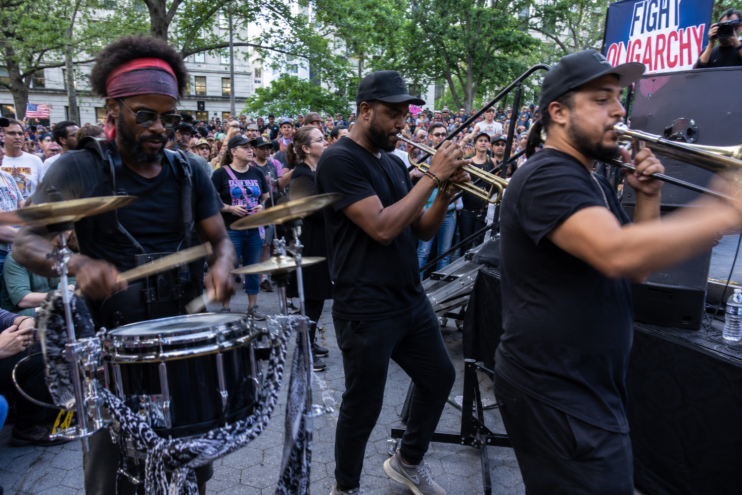 Live brass band performing drums and trumpet at an outdoor street protest crowd event.