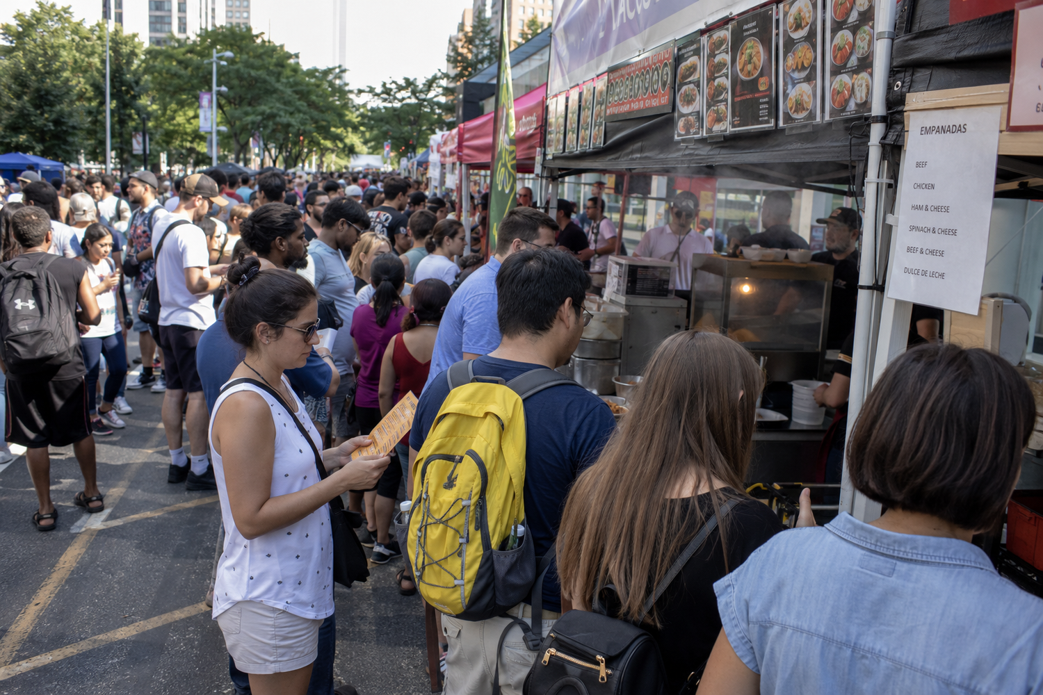 Crowds of people line up at outdoor food truck festival stalls on a busy urban street during summer.