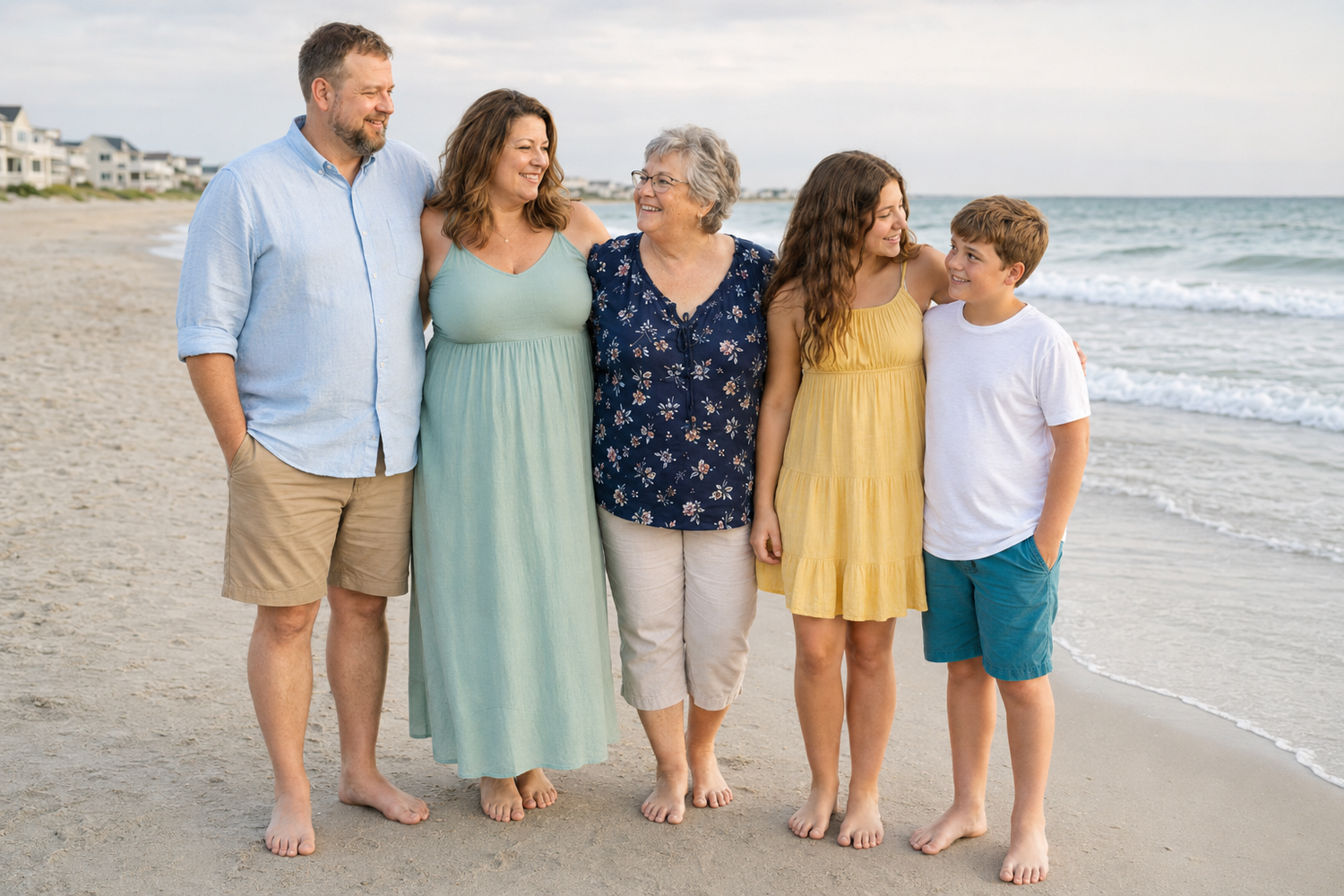 Five family members walking and smiling together on a beach, wearing colorful summer dresses and casual outfits.