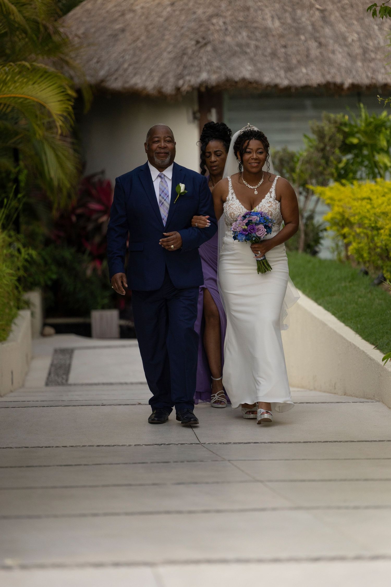 A couple in wedding attire descends outdoor steps together during a tropical destination wedding ceremony.