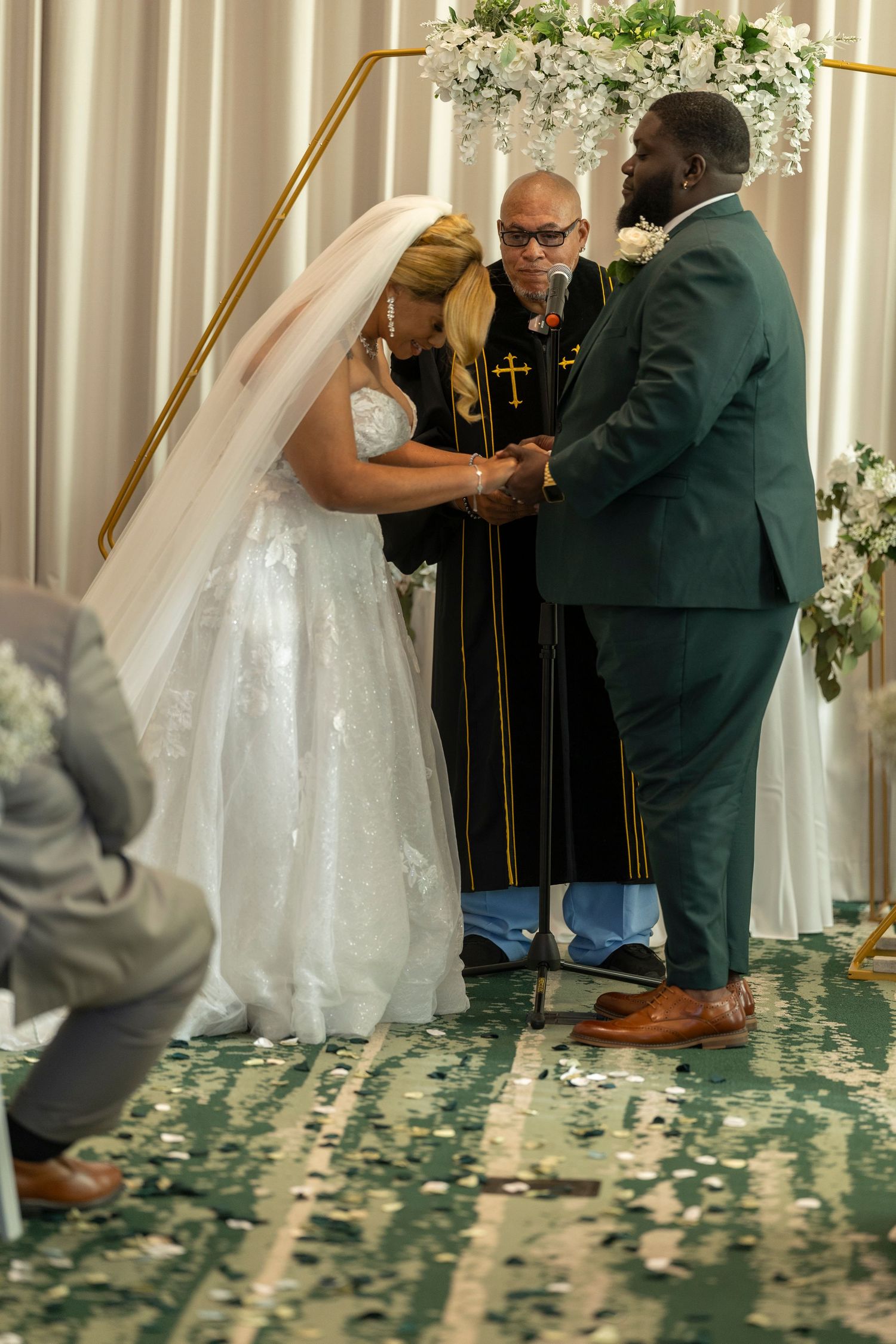 A wedding ceremony sequence showing the couple exchanging vows in front of an officiant with floral decorations.