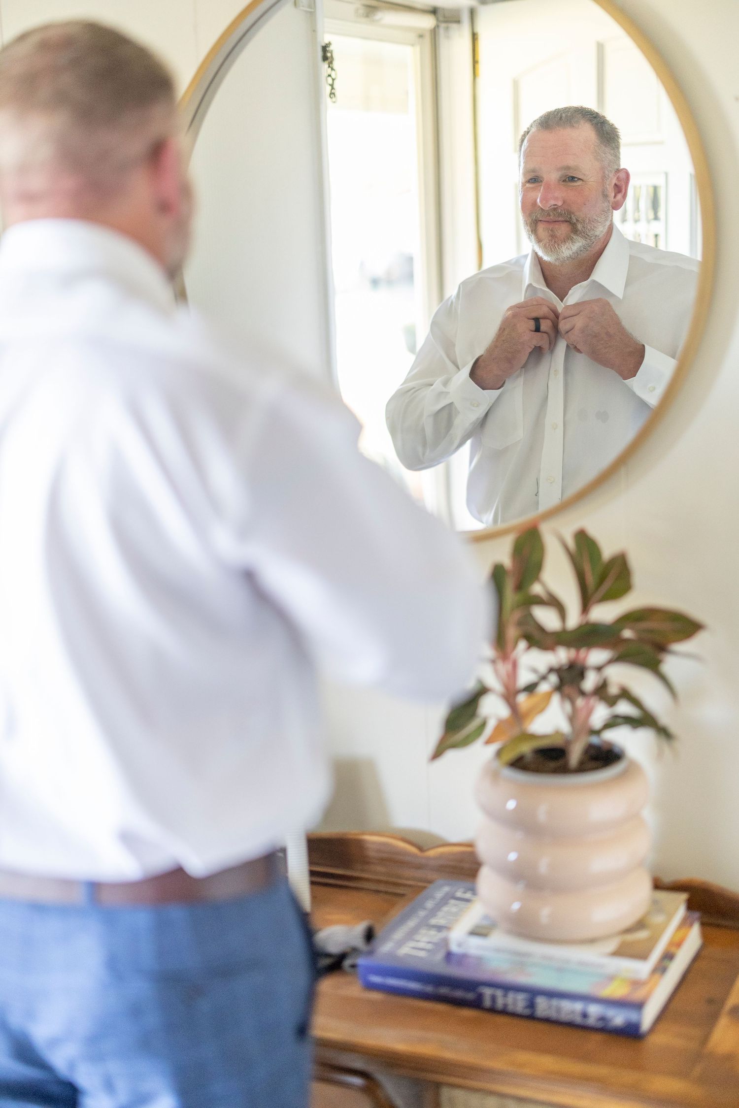Four sequential mirror reflections show a person in a white shirt and jeans shaving their face at a bathroom vanity.