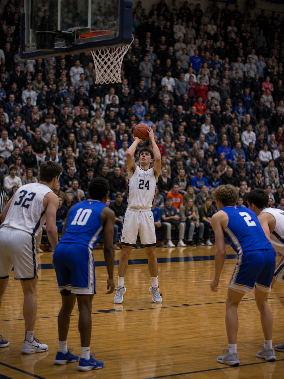Basketball player #24 shoots a free throw in a packed gym during an intense high school basketball game.