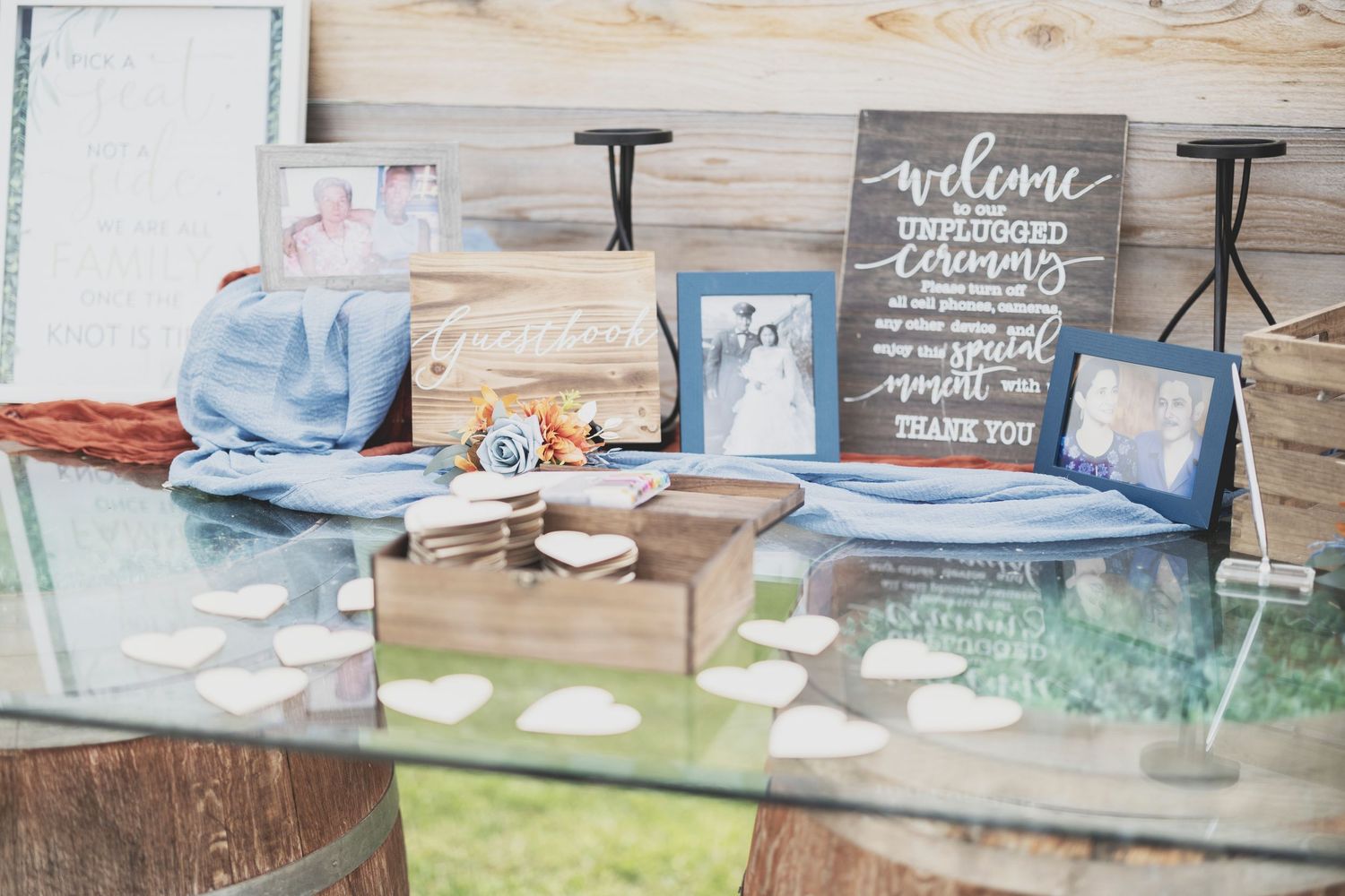 Wedding reception details with welcome sign, guest book table, and rustic decor at an outdoor venue.