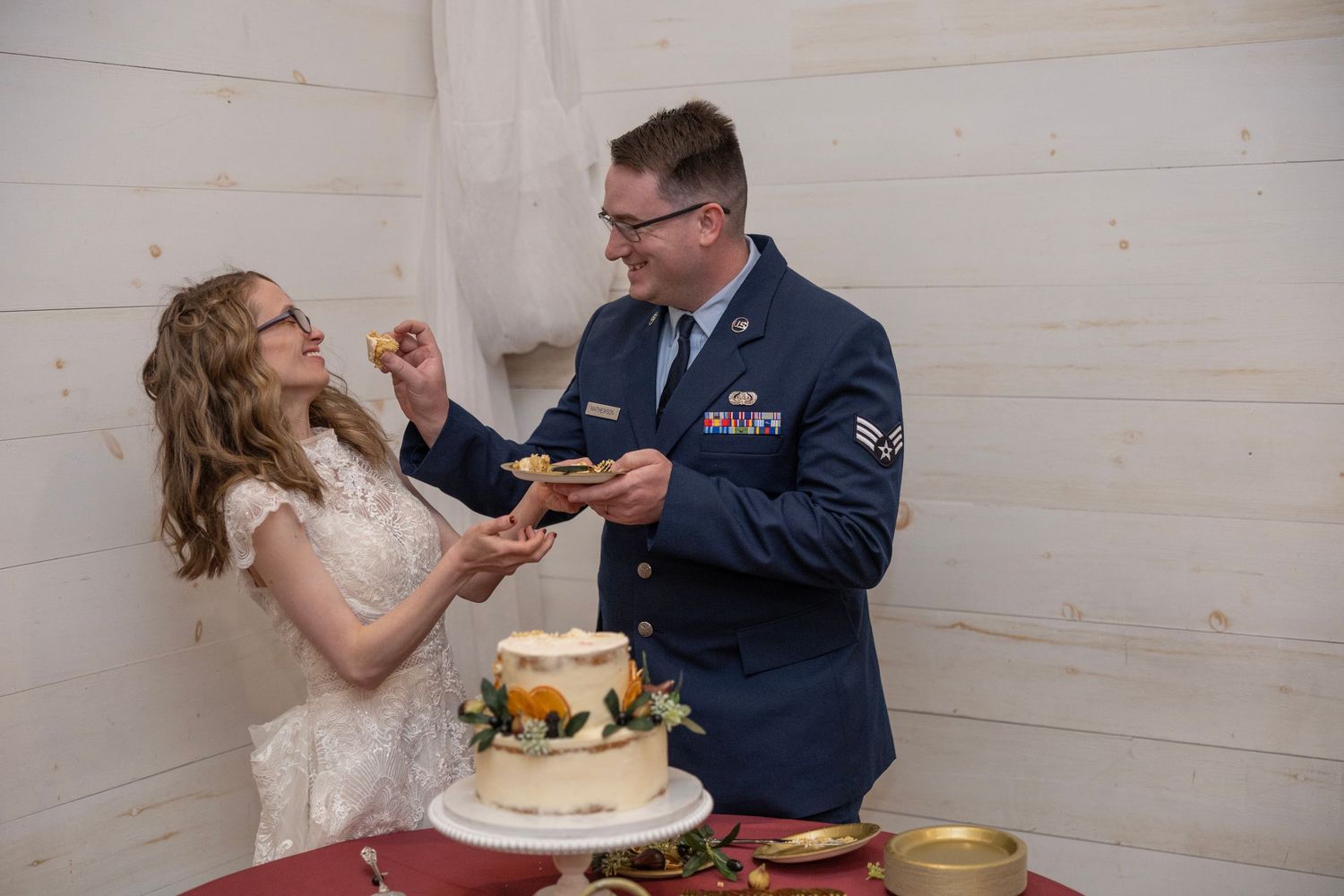 A couple in wedding attire feeds each other cake during their traditional cake cutting ceremony at a reception.