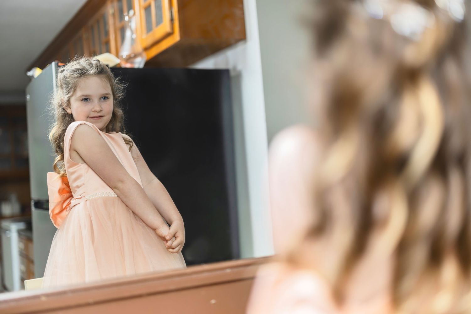 Young girl in a peach-colored dress poses on wooden stairs during a portrait photography session.