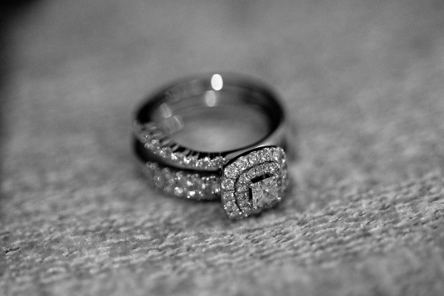 A collection of seven elegant diamond engagement rings arranged in a row on a textured gray background.