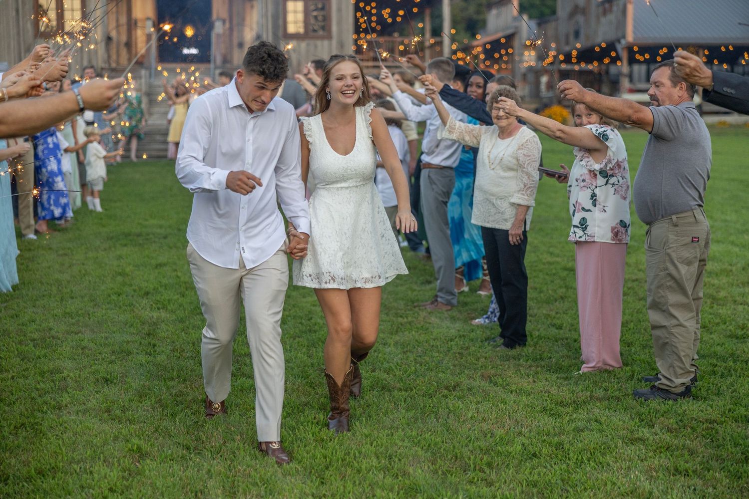 Outdoor wedding celebration with guests in casual attire walking on a grassy lawn during a sunny afternoon.
