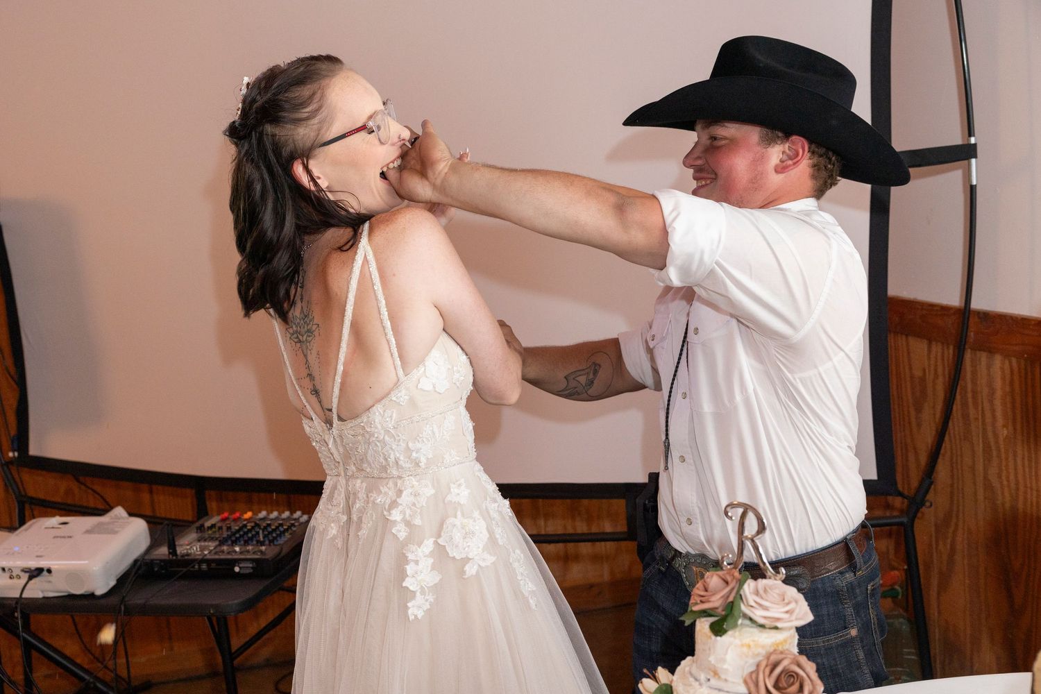 A couple shares a playful moment while dancing at a casual rustic reception.