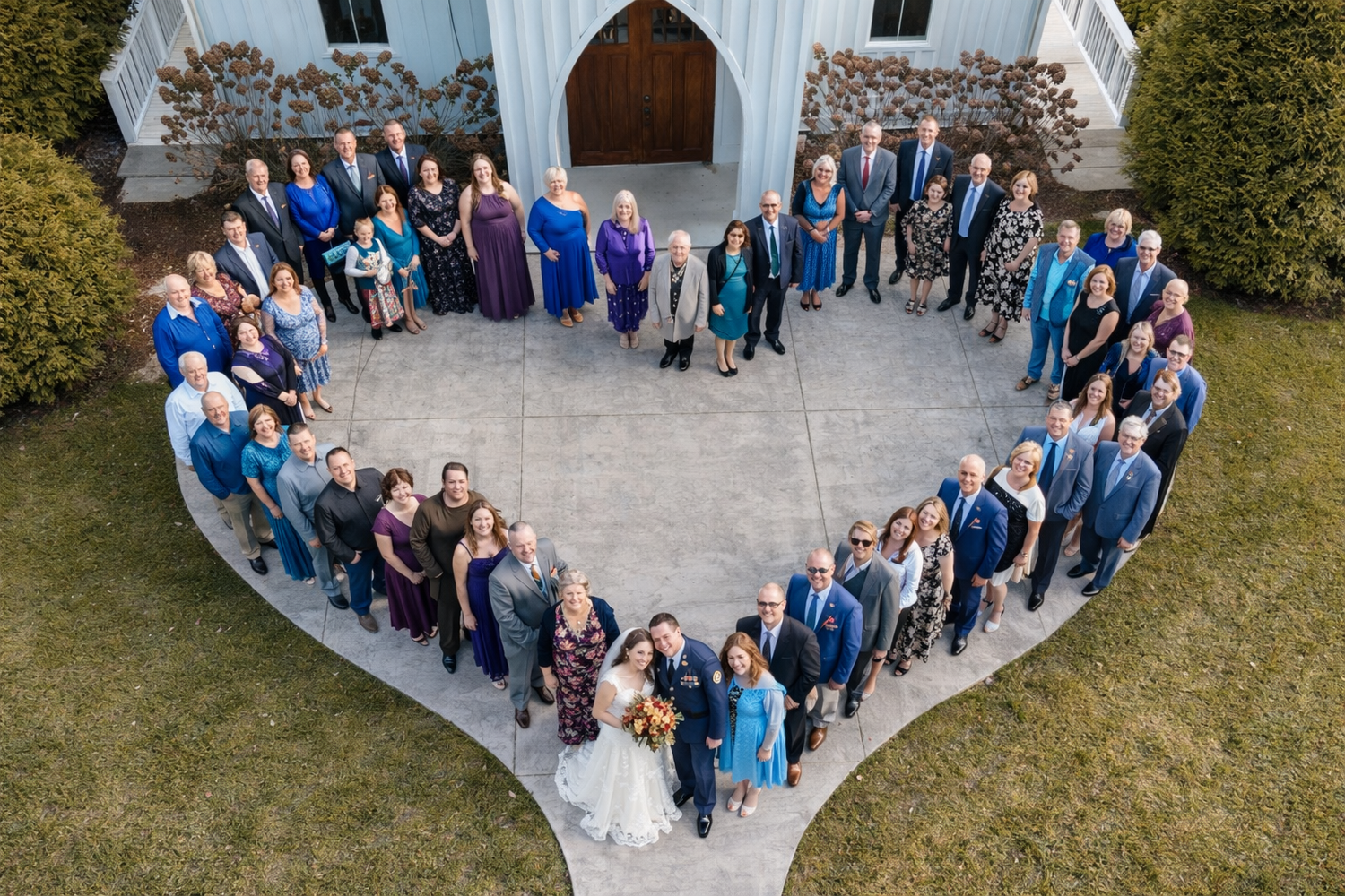 Wedding party members gather in a curved formation on a stone patio near a white gazebo during an outdoor celebration.