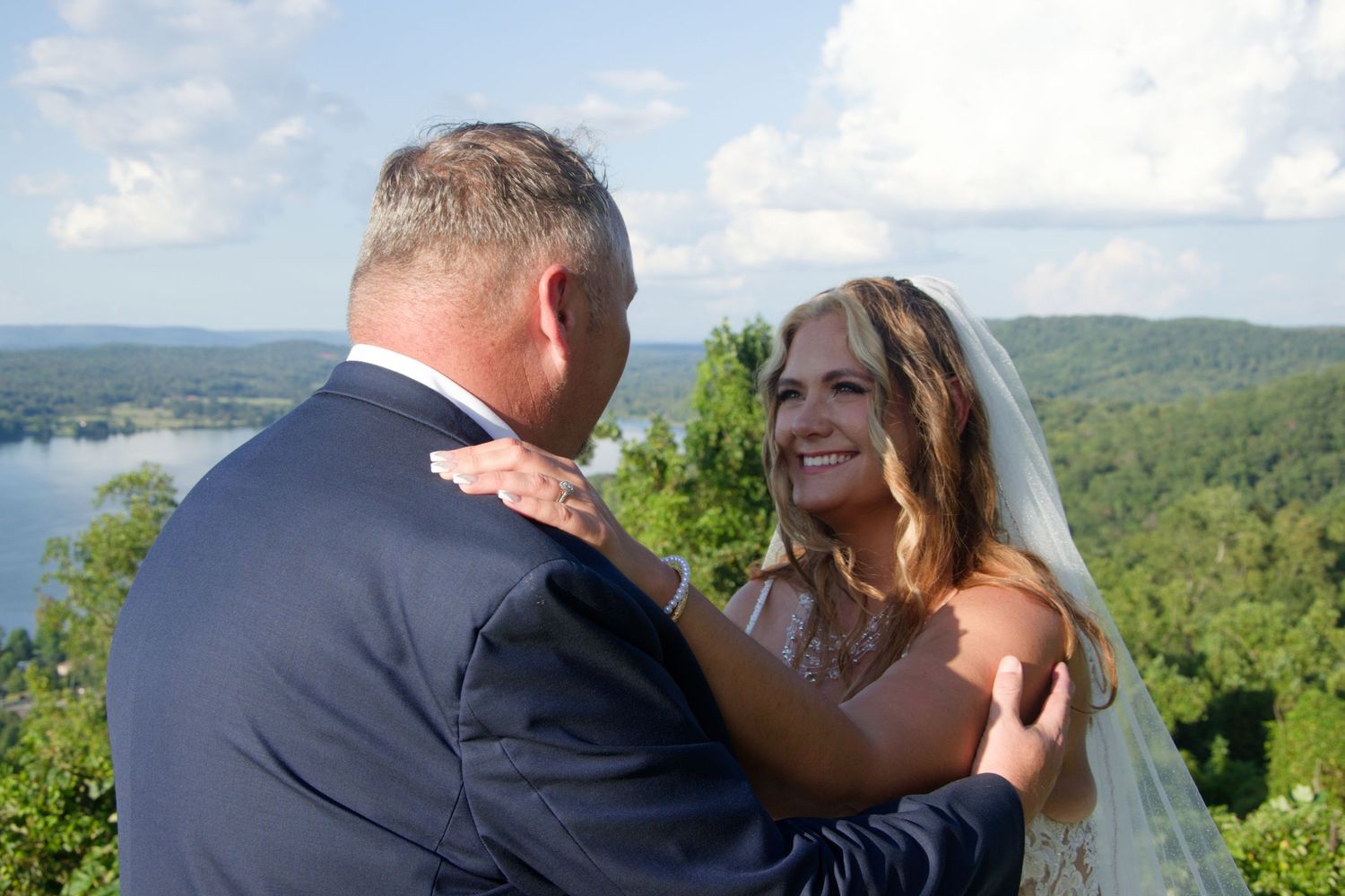 Newlywed couple shares romantic moments overlooking a scenic mountain landscape on their wedding day.
