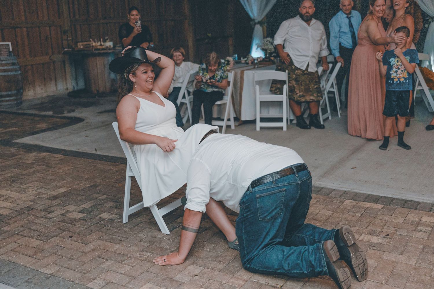 A couple shares a tender moment during a dance at an outdoor wedding reception on a rustic brick patio.