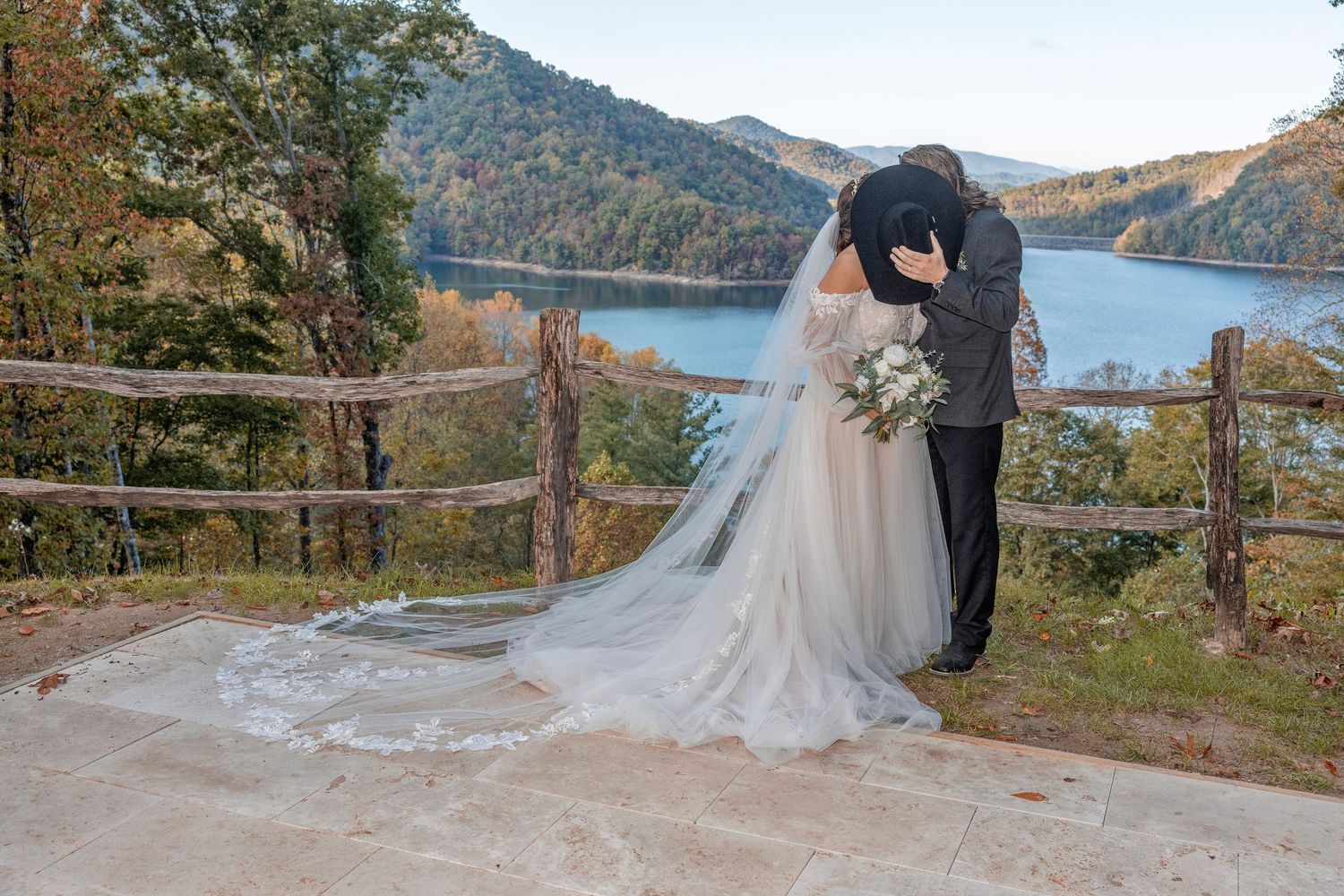Scenic mountain wedding photos taken at an overlook with lake views and fall foliage in the background.