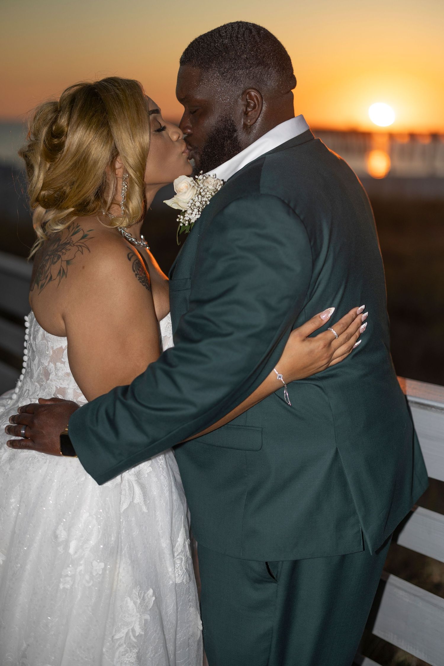 A couple shares a romantic dance at sunset during their wedding celebration with golden light illuminating the background.