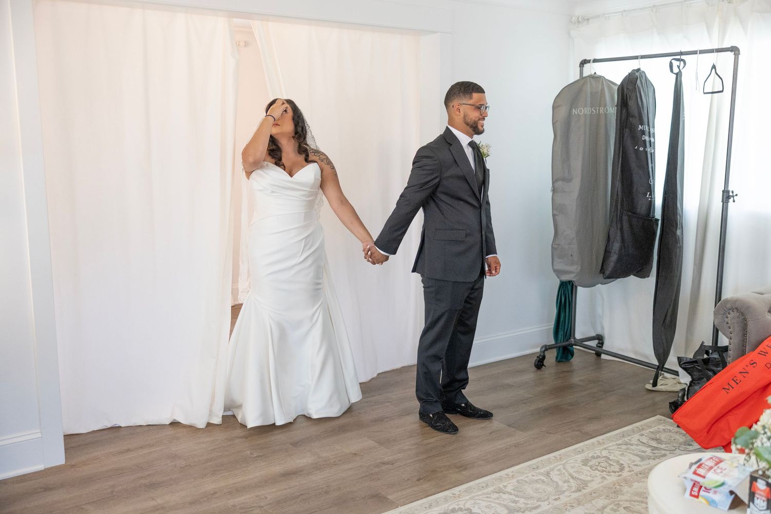 A couple dances together in an elegant white studio space with hardwood floors and natural lighting.