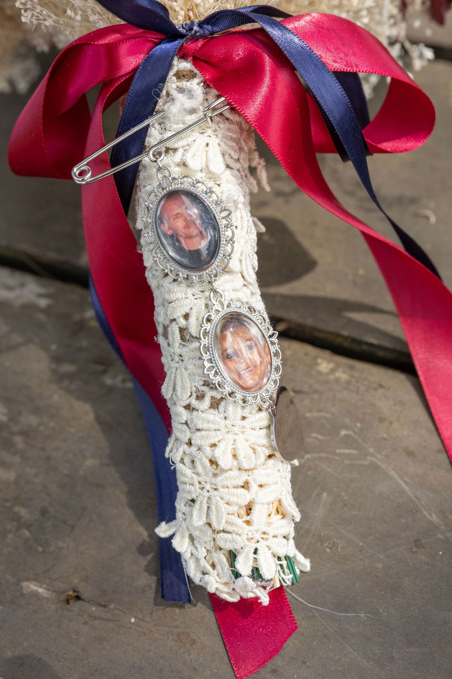 White lace bouquet wrap adorned with two portrait medallions and red and navy blue satin ribbons.