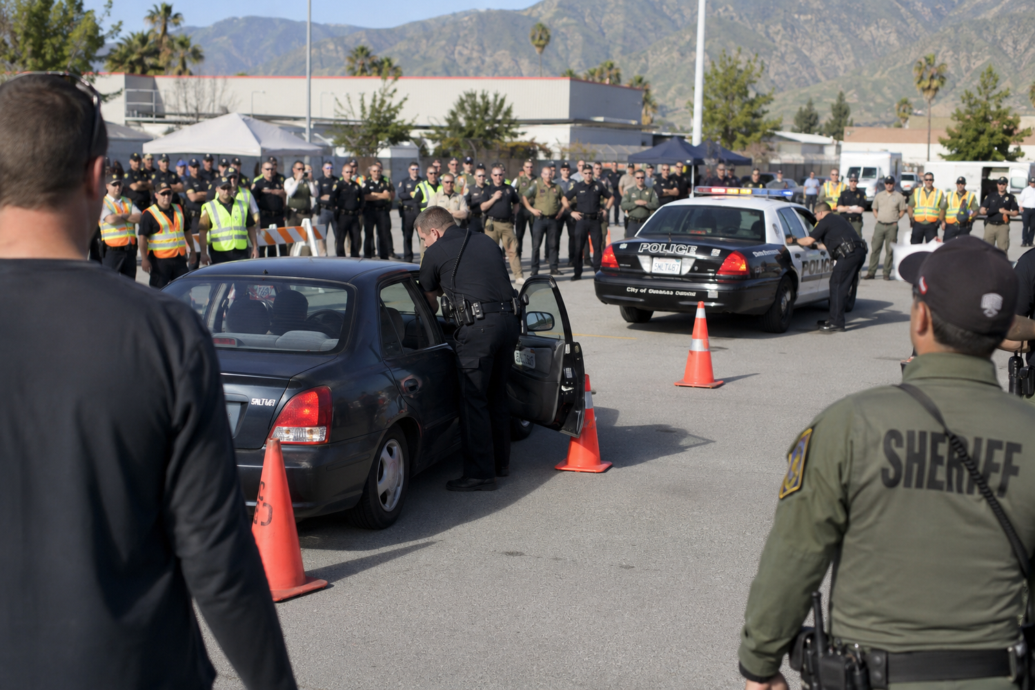 Sheriff deputies conducting a vehicle search in a parking lot during a law enforcement operation.