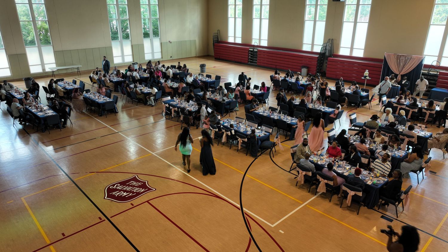 Aerial view of a school gymnasium transformed into a banquet hall with multiple tables and seated guests.
