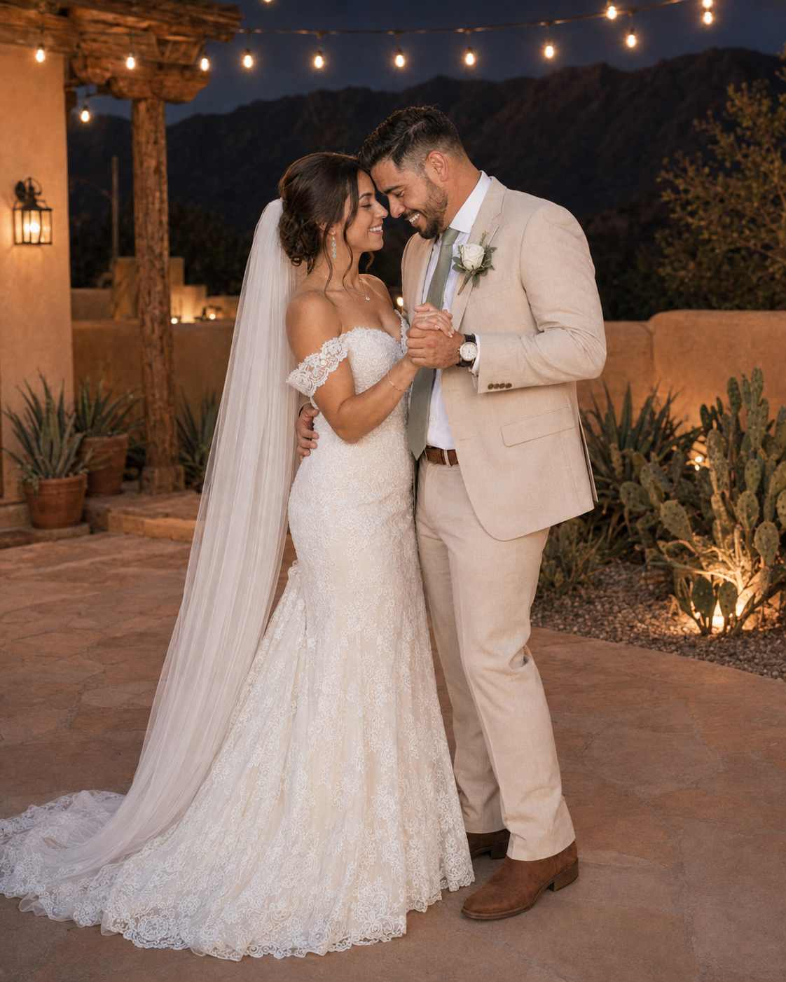 Bride and groom share first dance outdoors at desert wedding venue with string lights and cacti at night.