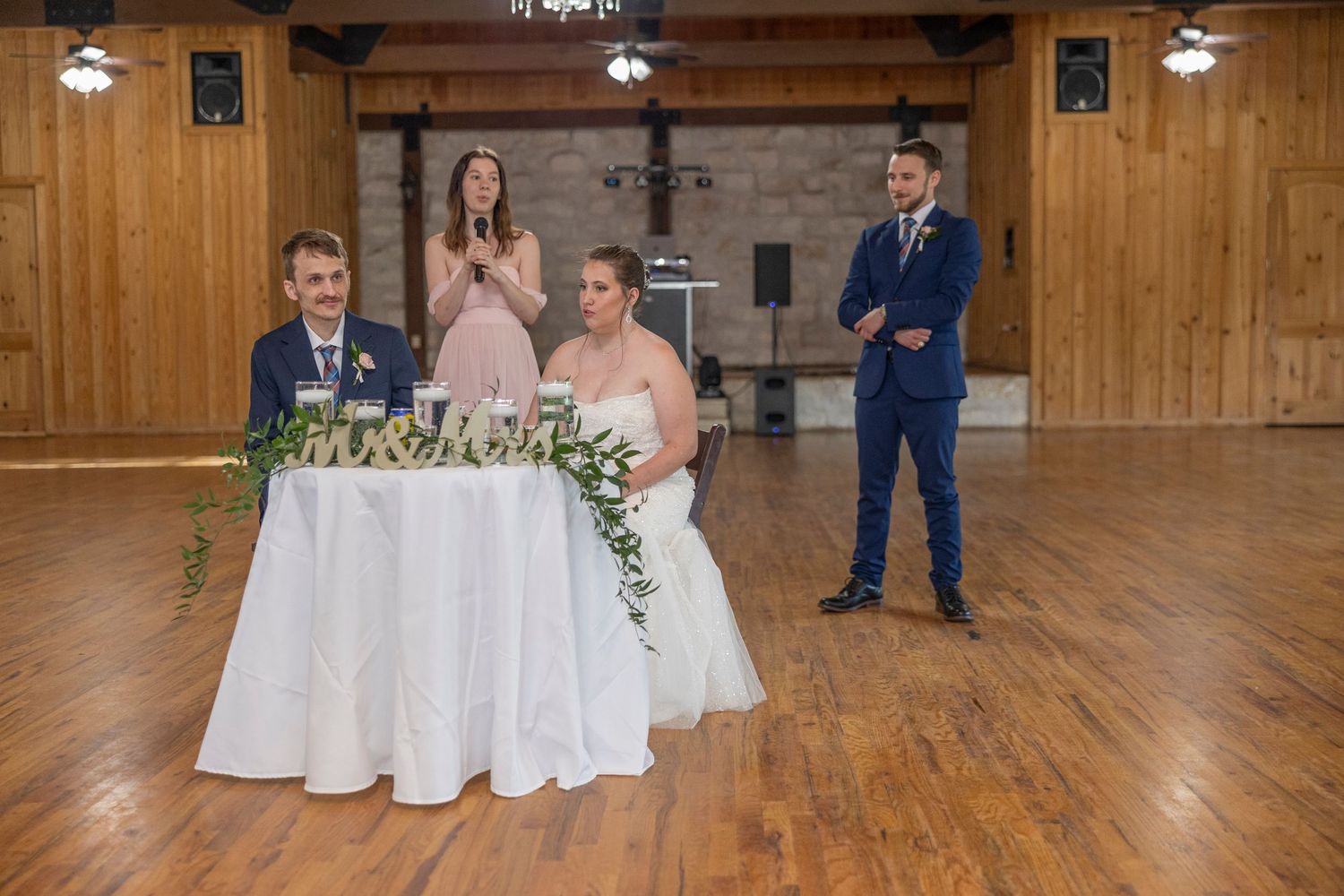 A wedding ceremony in a rustic wooden barn venue with decorative floral arrangements and elegant white decor.