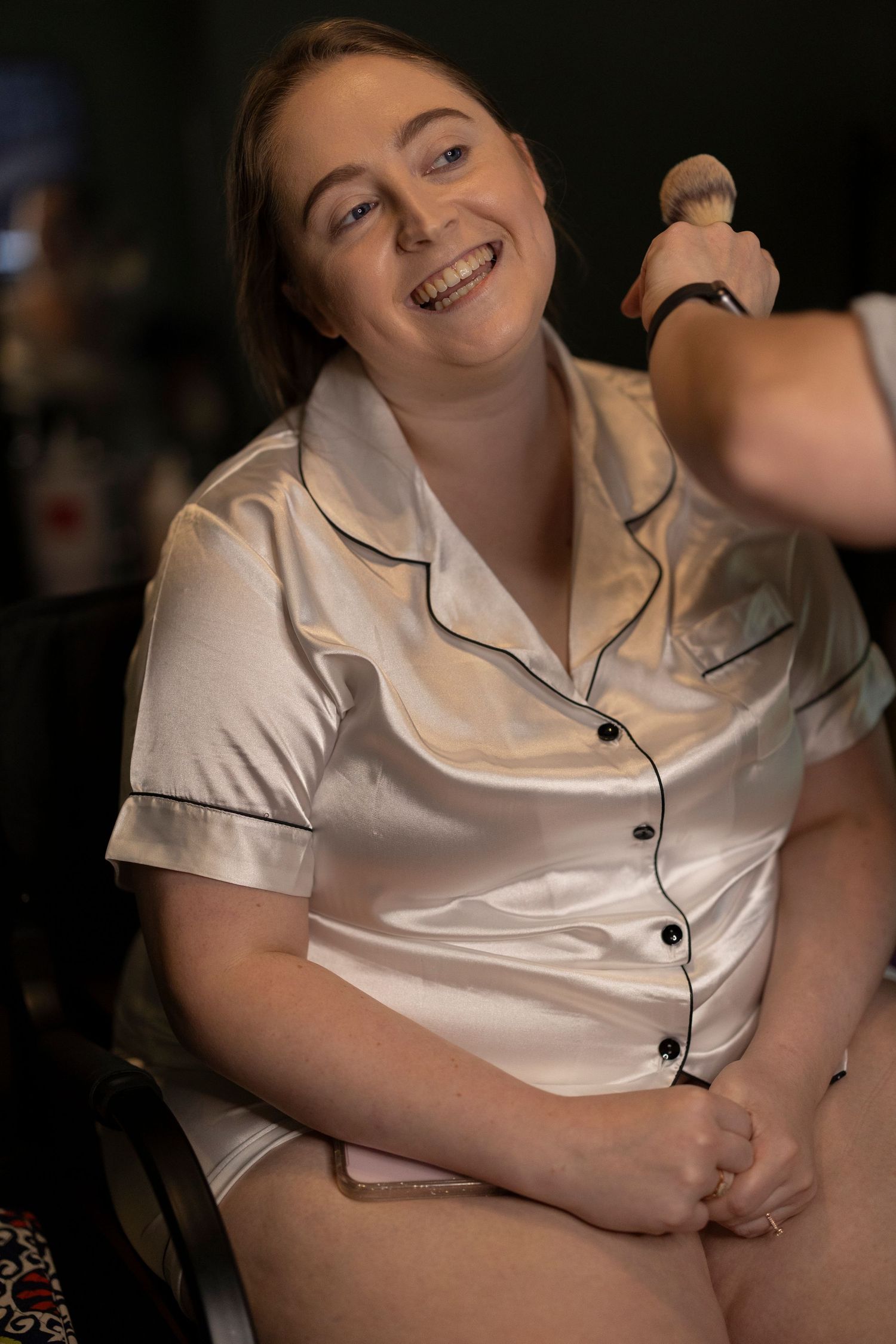 Someone wearing a silky cream colored pajama top smiles warmly during a casual moment.