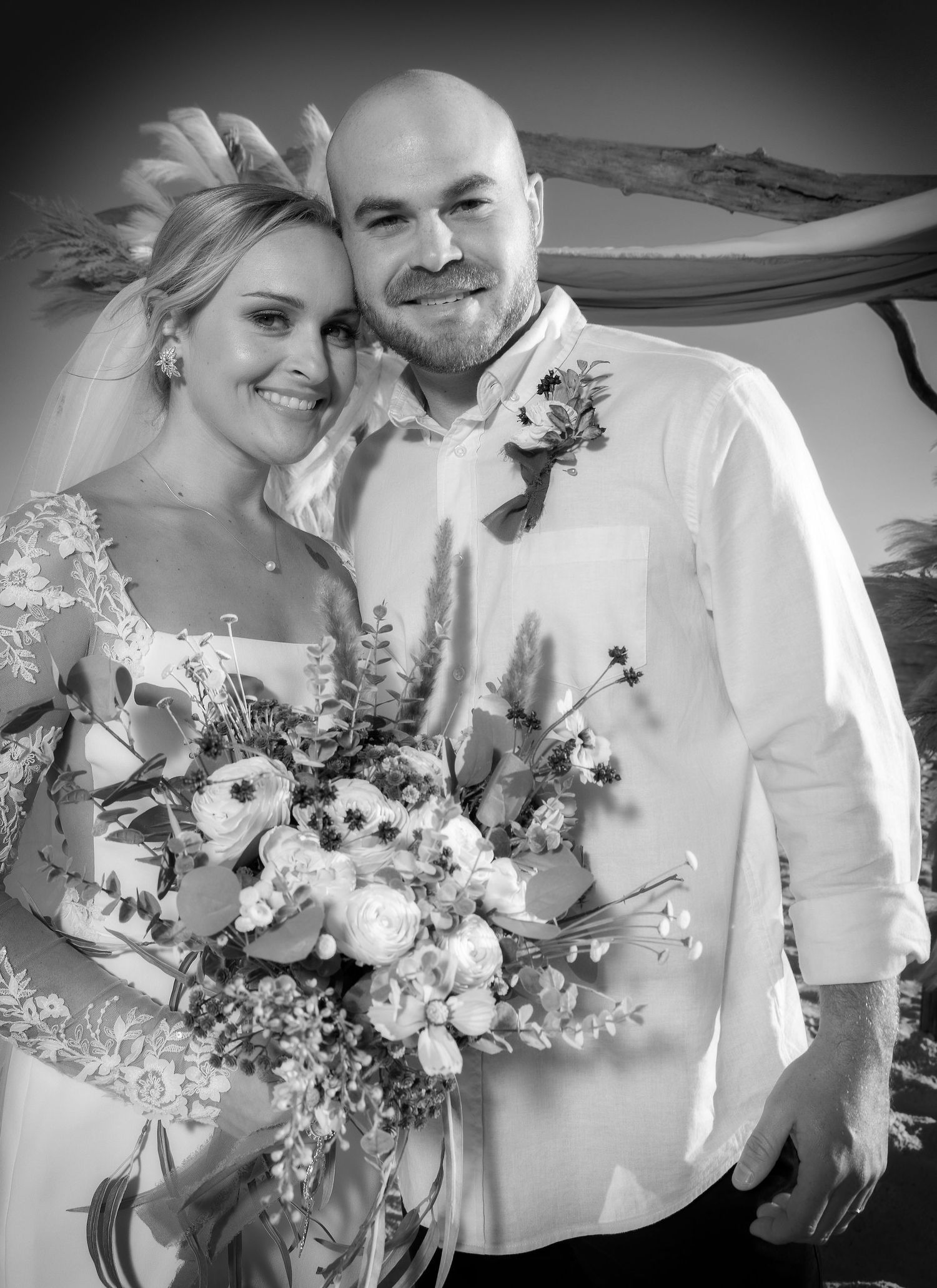 Black and white wedding photo showing a happy couple with the bride holding a beautiful floral bouquet.
