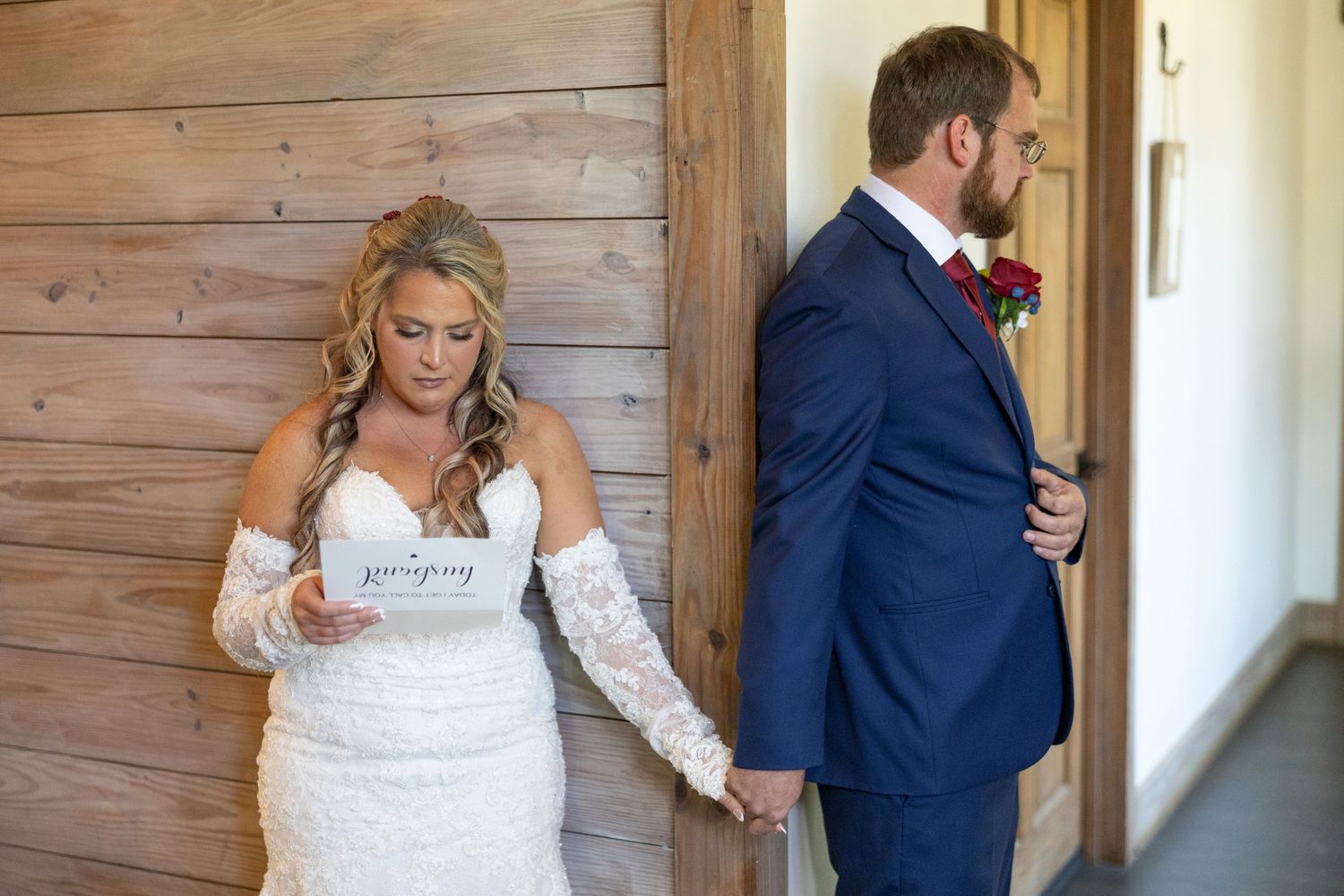 A couple in wedding attire walking through a rustic wooden hallway.