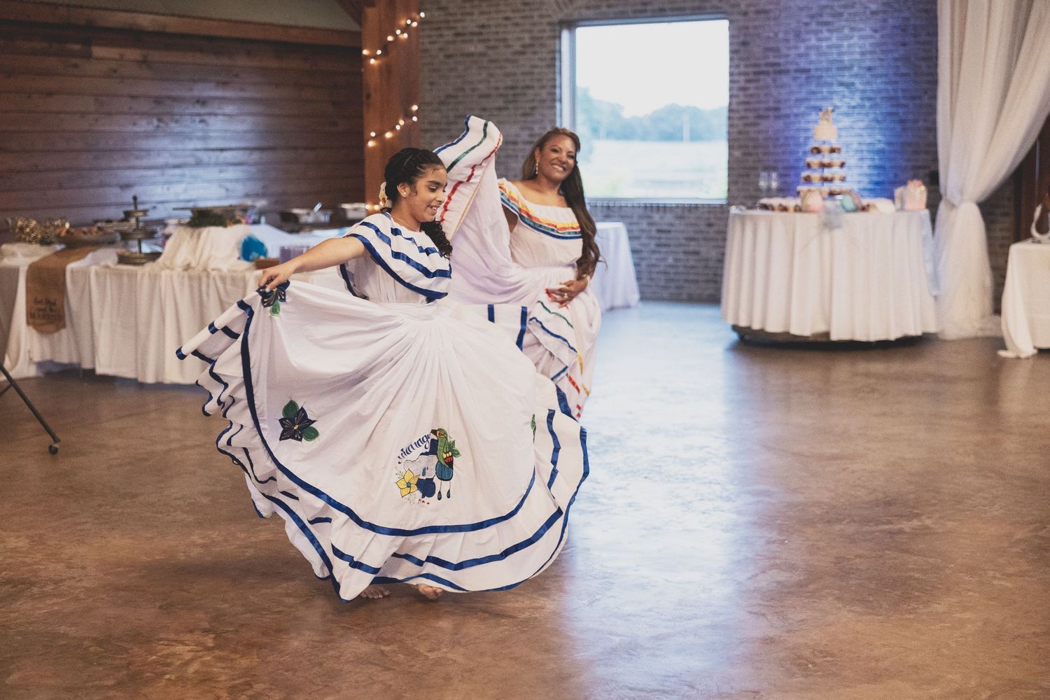A couple performs a traditional dance in a ballroom with spinning white dresses and elegant movements.