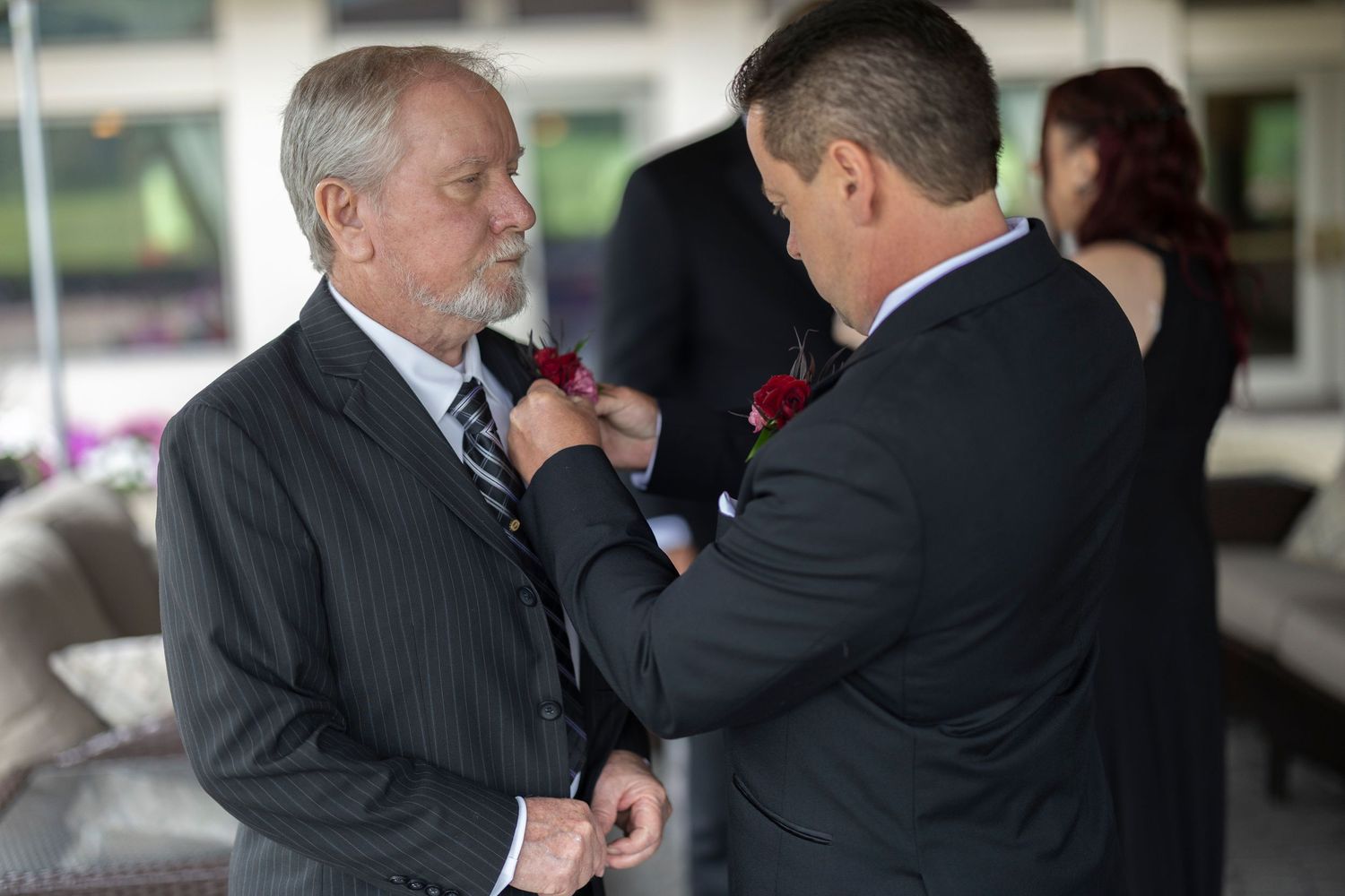 Two people in business attire shake hands and exchange greetings in a professional setting.