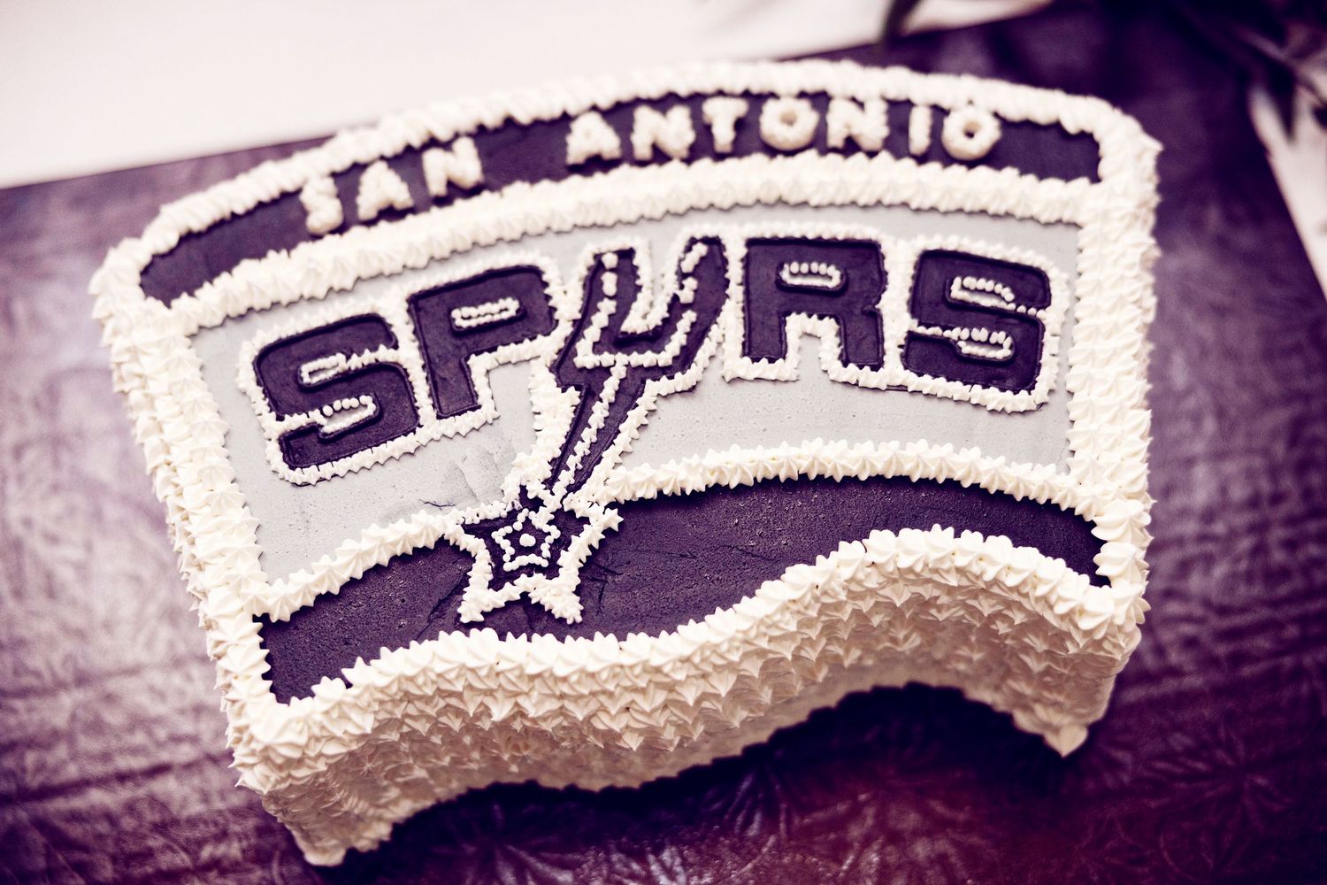 A row of vintage San Antonio Spurs NBA team logos and text embroidered on white fabric.