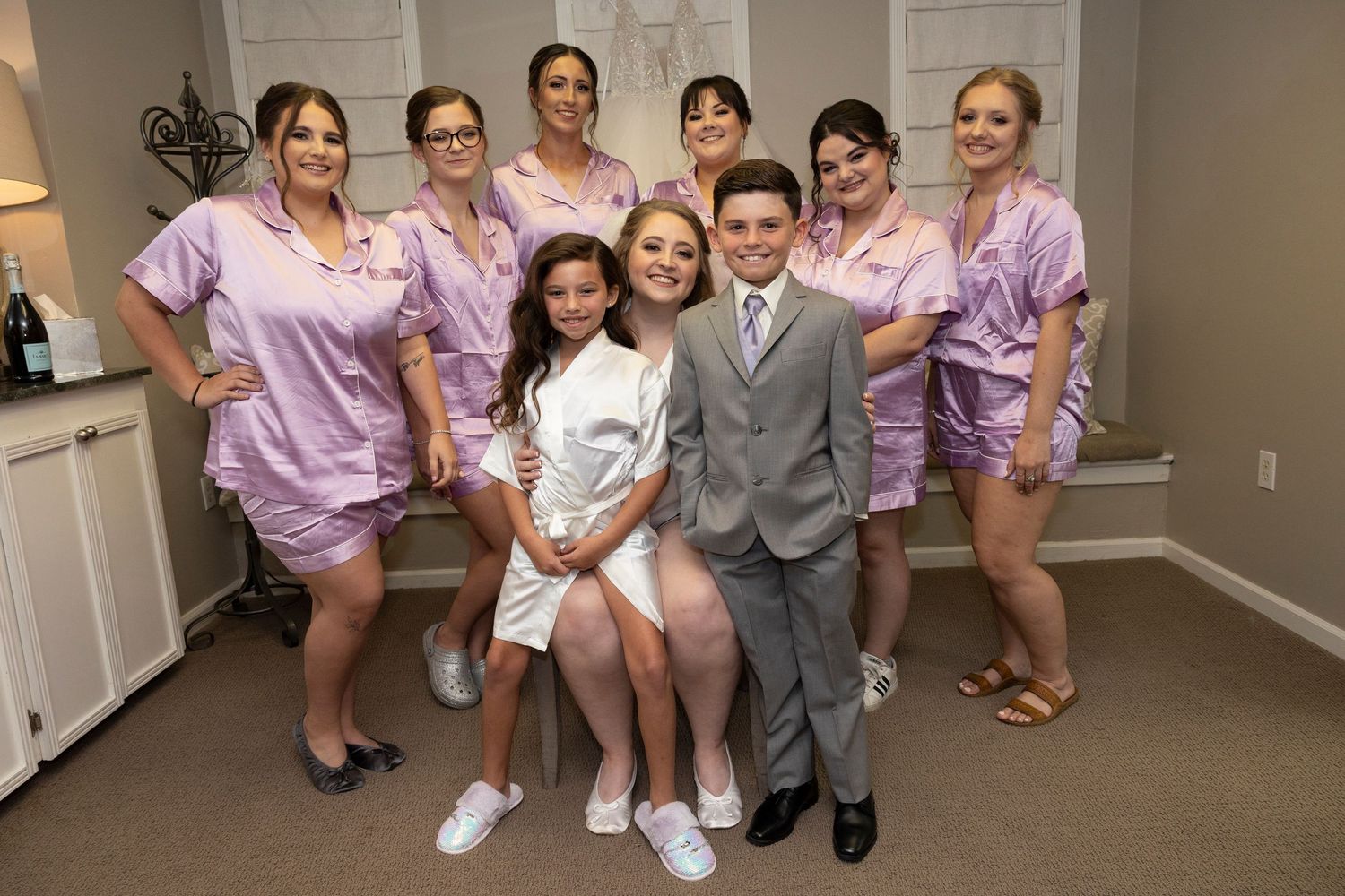 Wedding party poses together, with bridesmaids in lavender dresses surrounding the couple in formal attire.