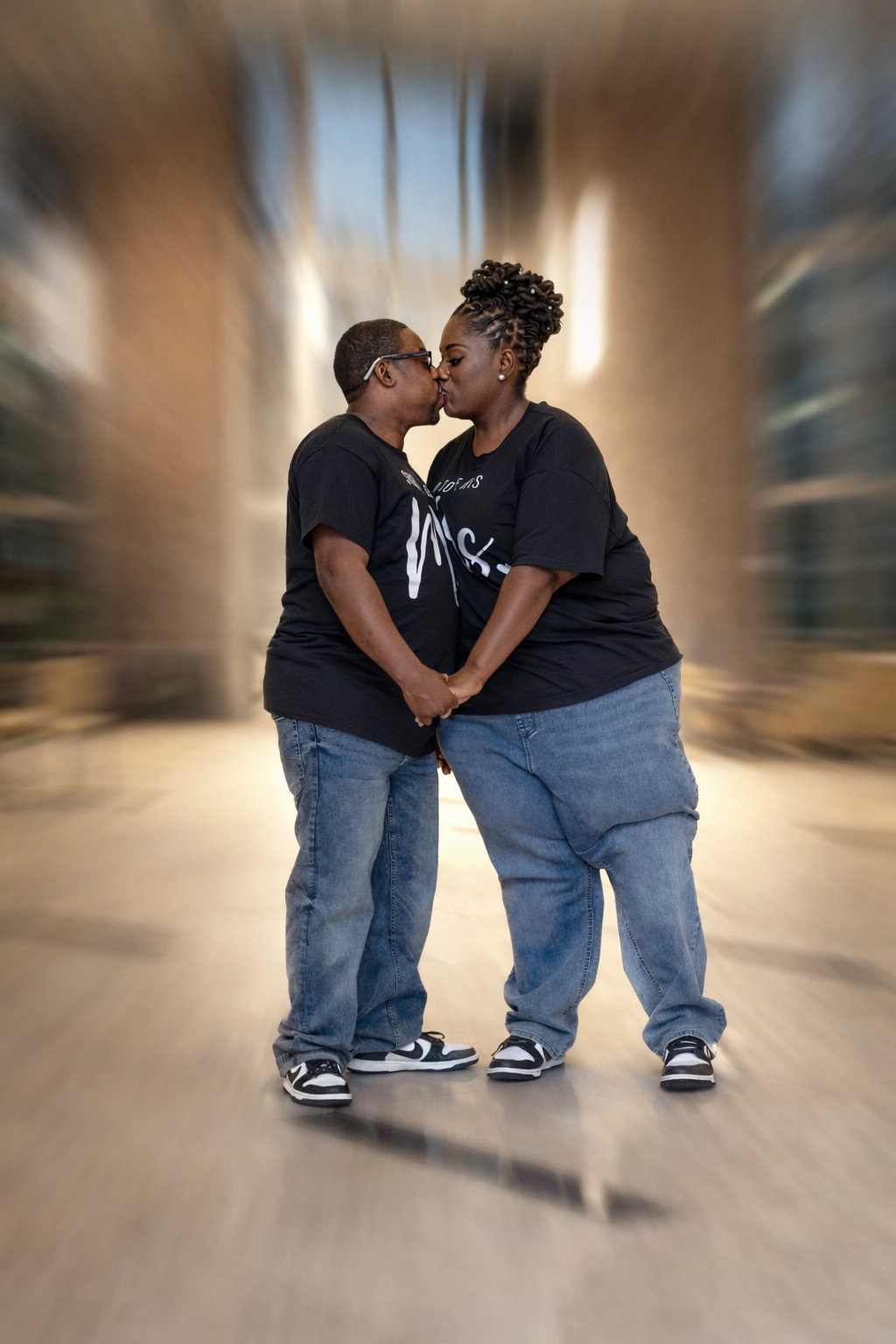 Two young children in matching outfits share a sweet moment together in a blurred background setting.