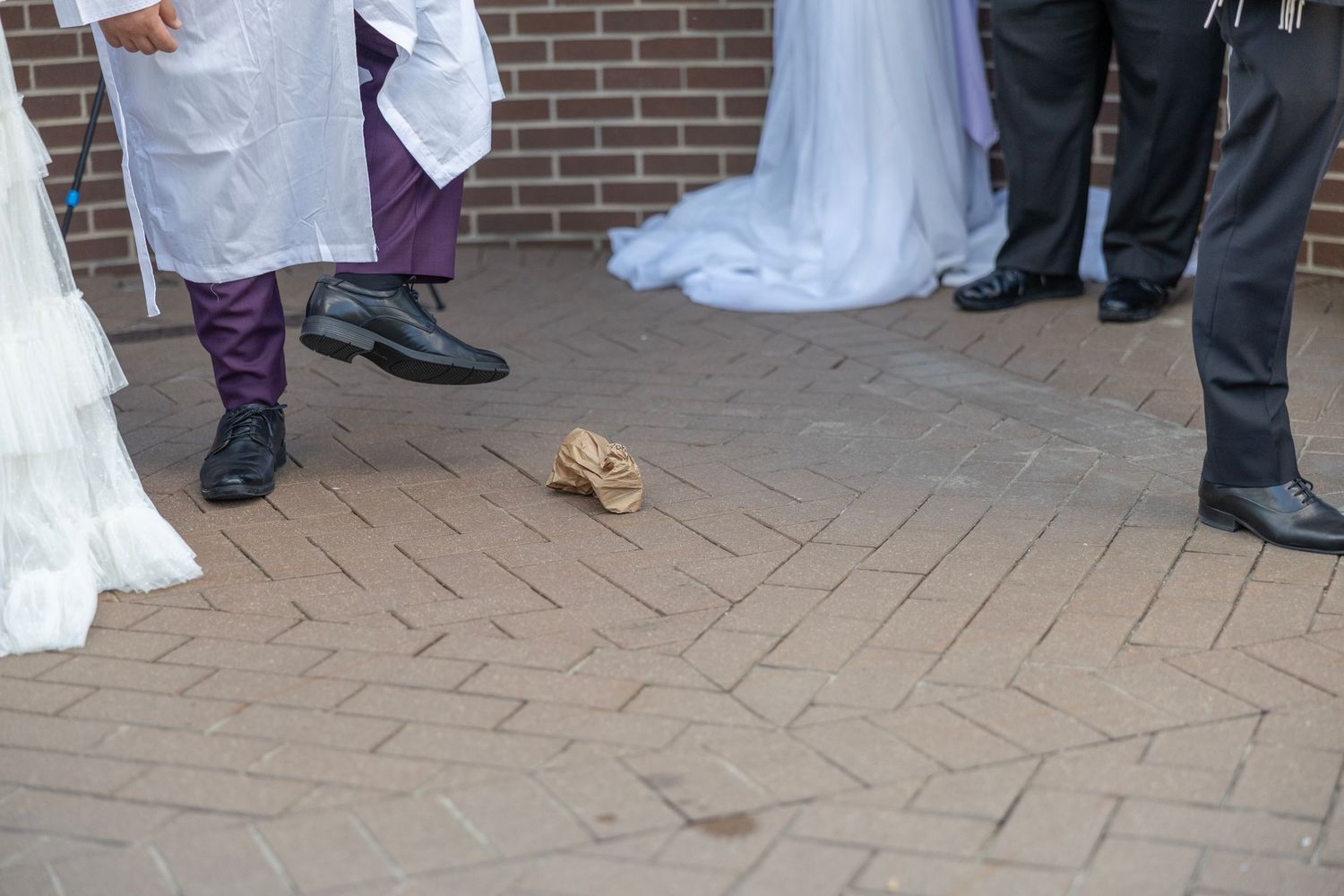 A bride and groom cut their elegant white wedding cake together at an outdoor reception venue.